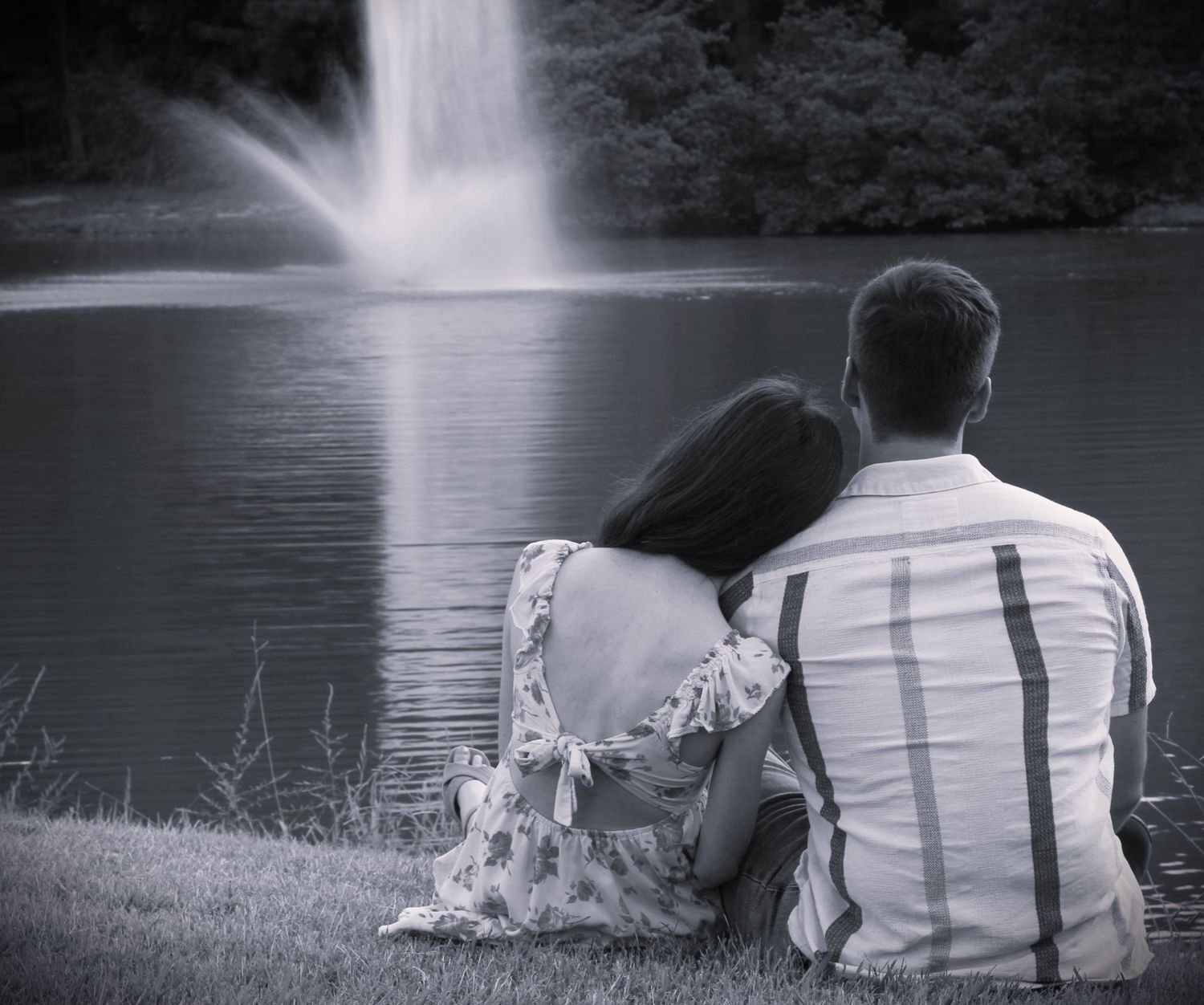 Goochland, VA Couple- Man and woman sitting down looking out toward a lake with a fountain in the center.