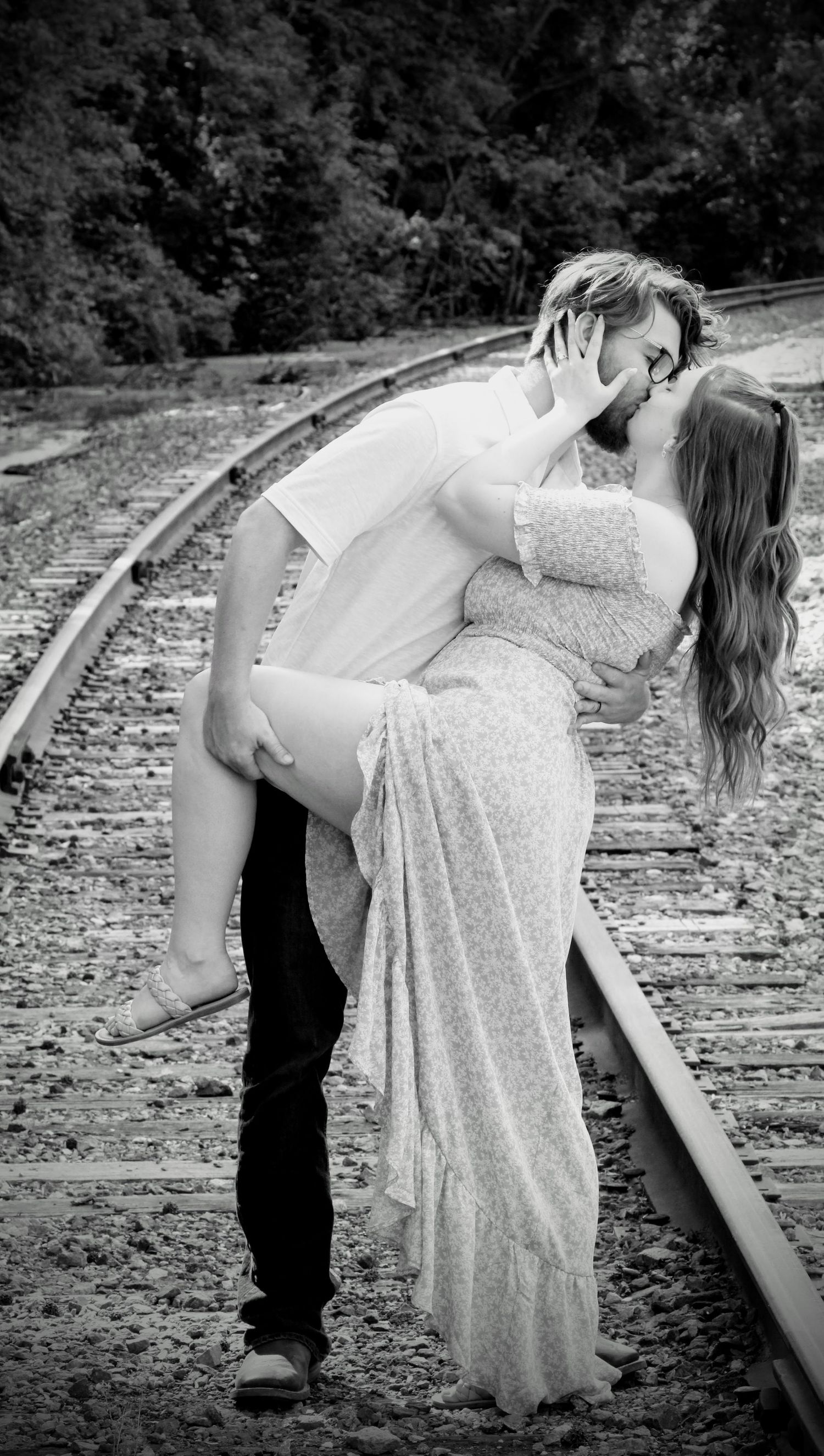 New Kent, VA engagement- Black & white, couple kissing on railroad track with him holding her leg up and dipping her.