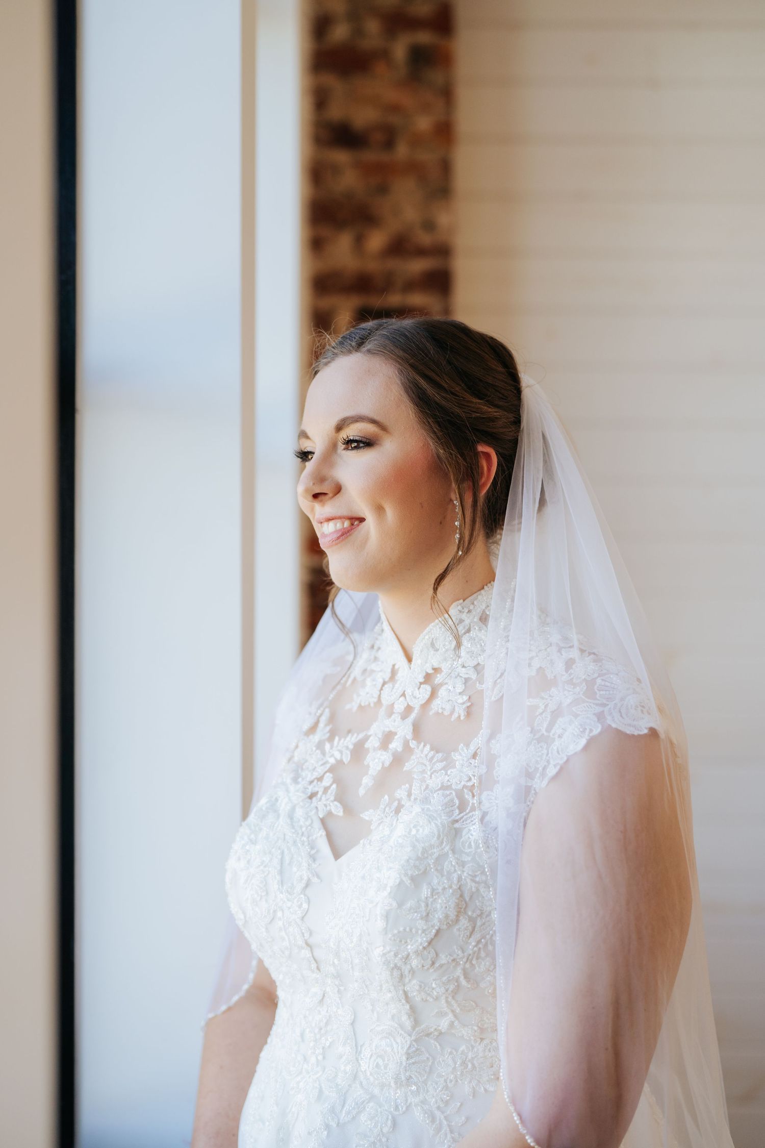 Elegant lace wedding dress with delicate details and flowing veil captured in natural light.