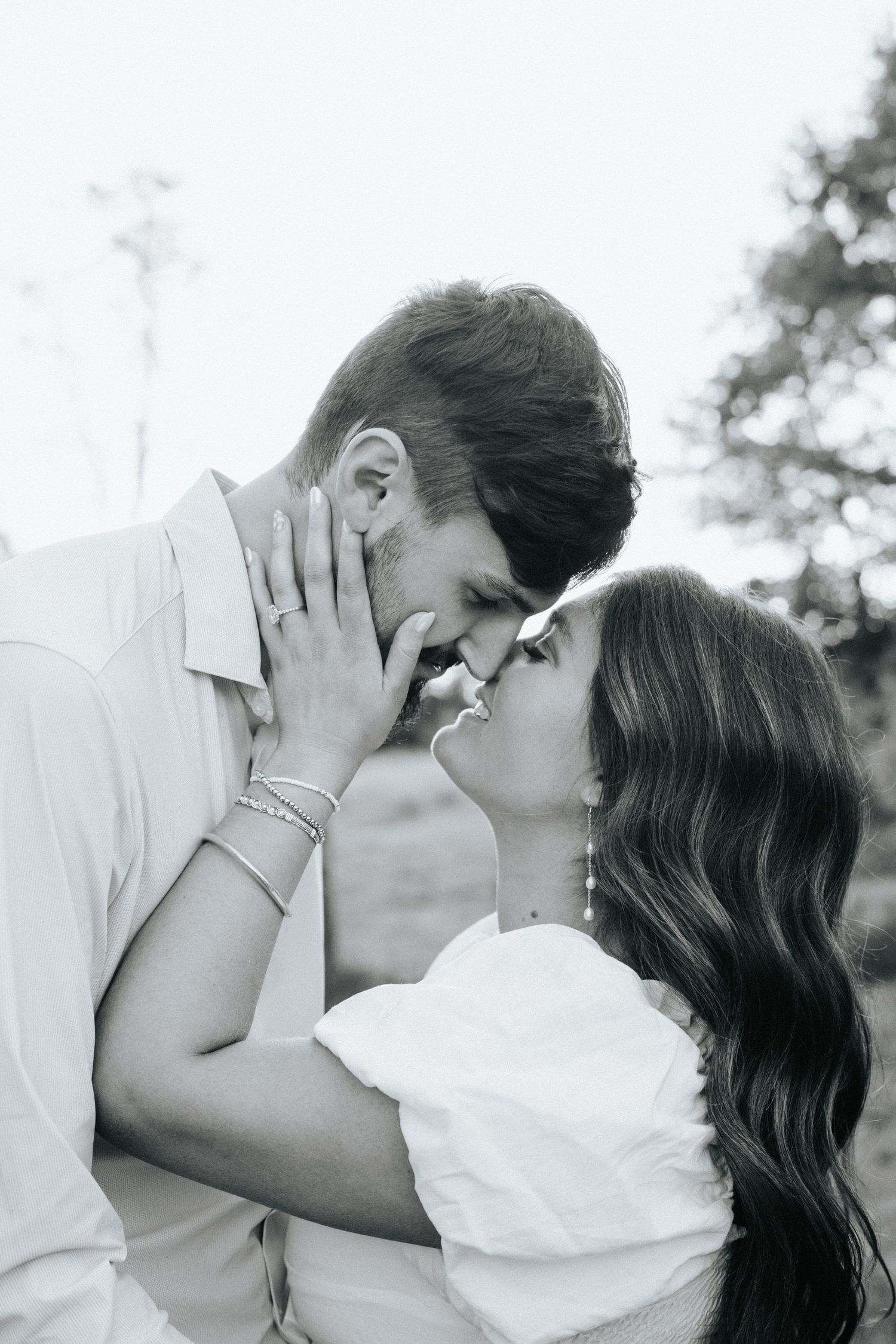 A romantic black and white photo series showing a couple sharing tender kisses against a light background.