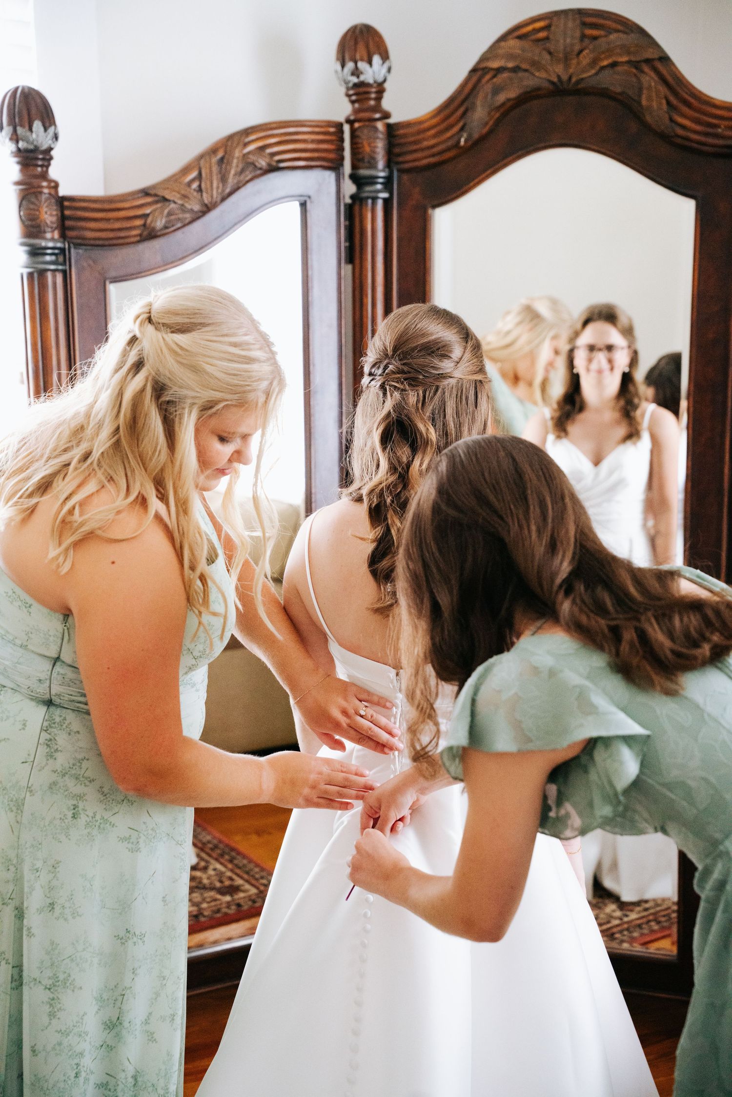 Bridesmaids in mint green dresses help zip up a white wedding gown in a series of connected photos.