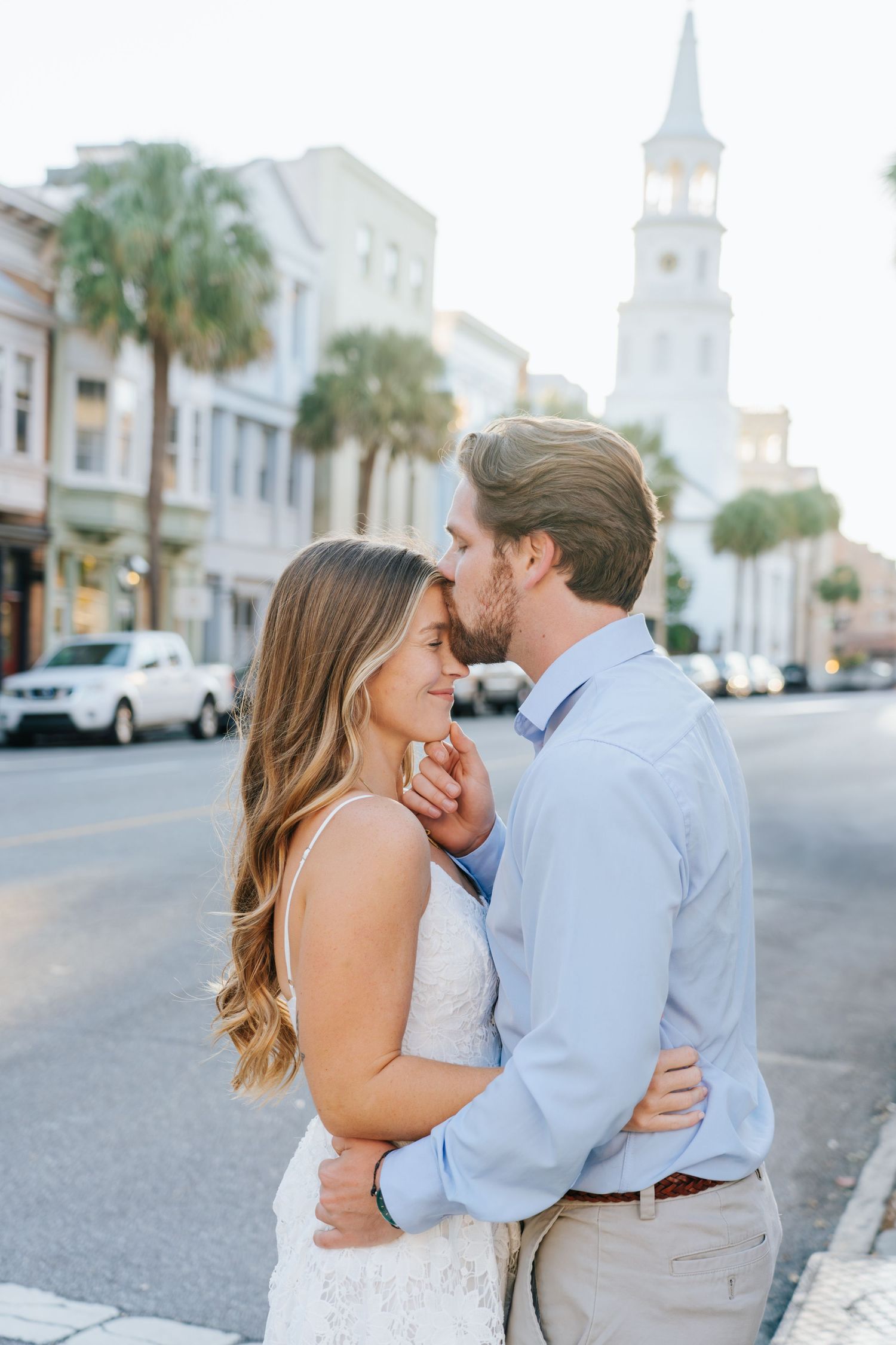 A sweet embrace captured on a Charleston street with historic church steeples in the background.