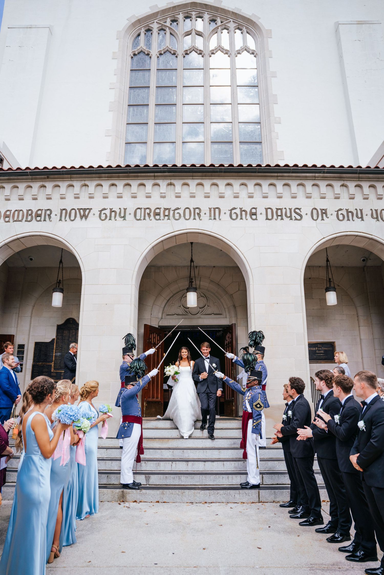 Wedding party members in blue dresses and dark suits line up outside the Citadel chapel.