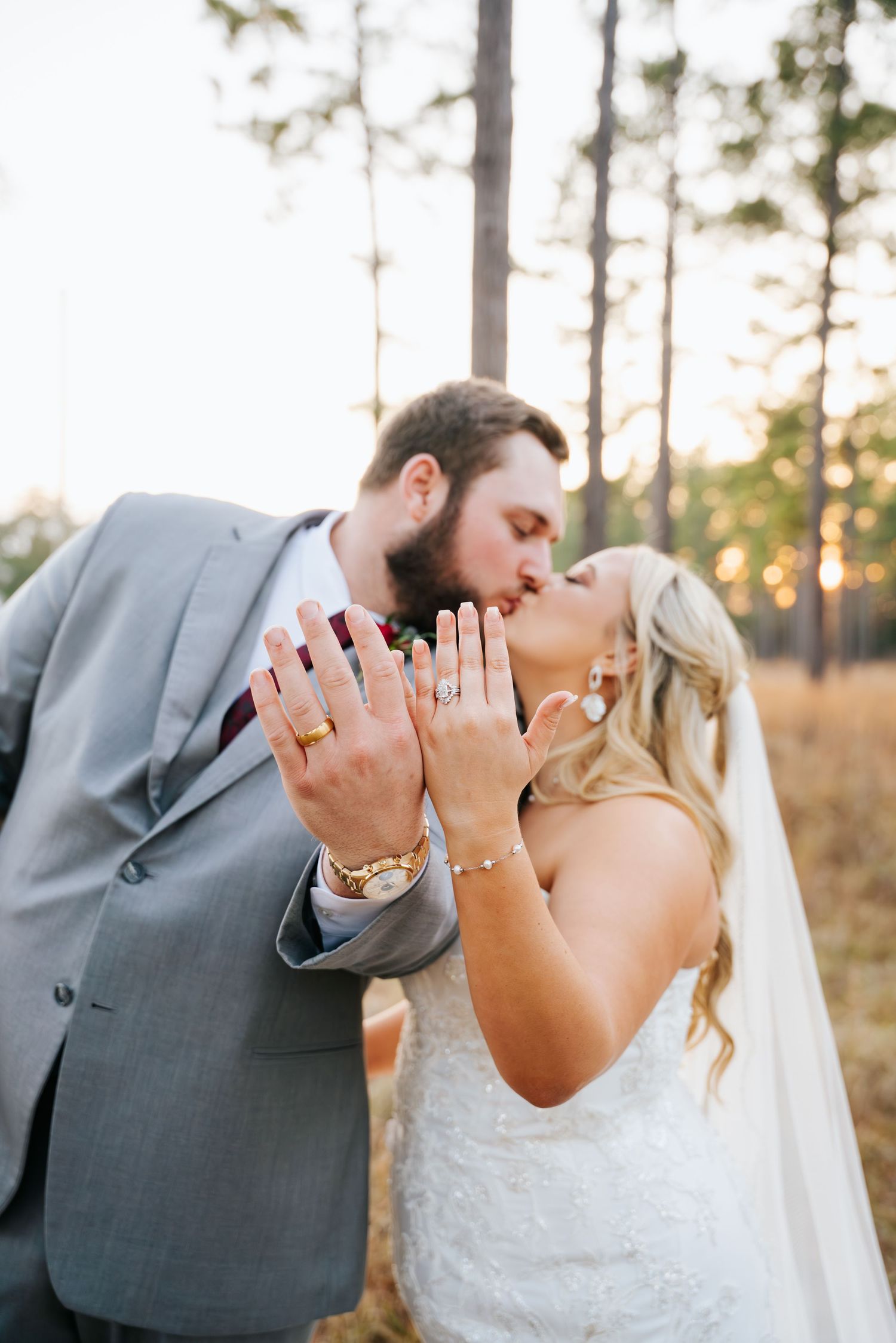 Romantic wedding couple shares three sweet kisses in a pine forest at sunset.