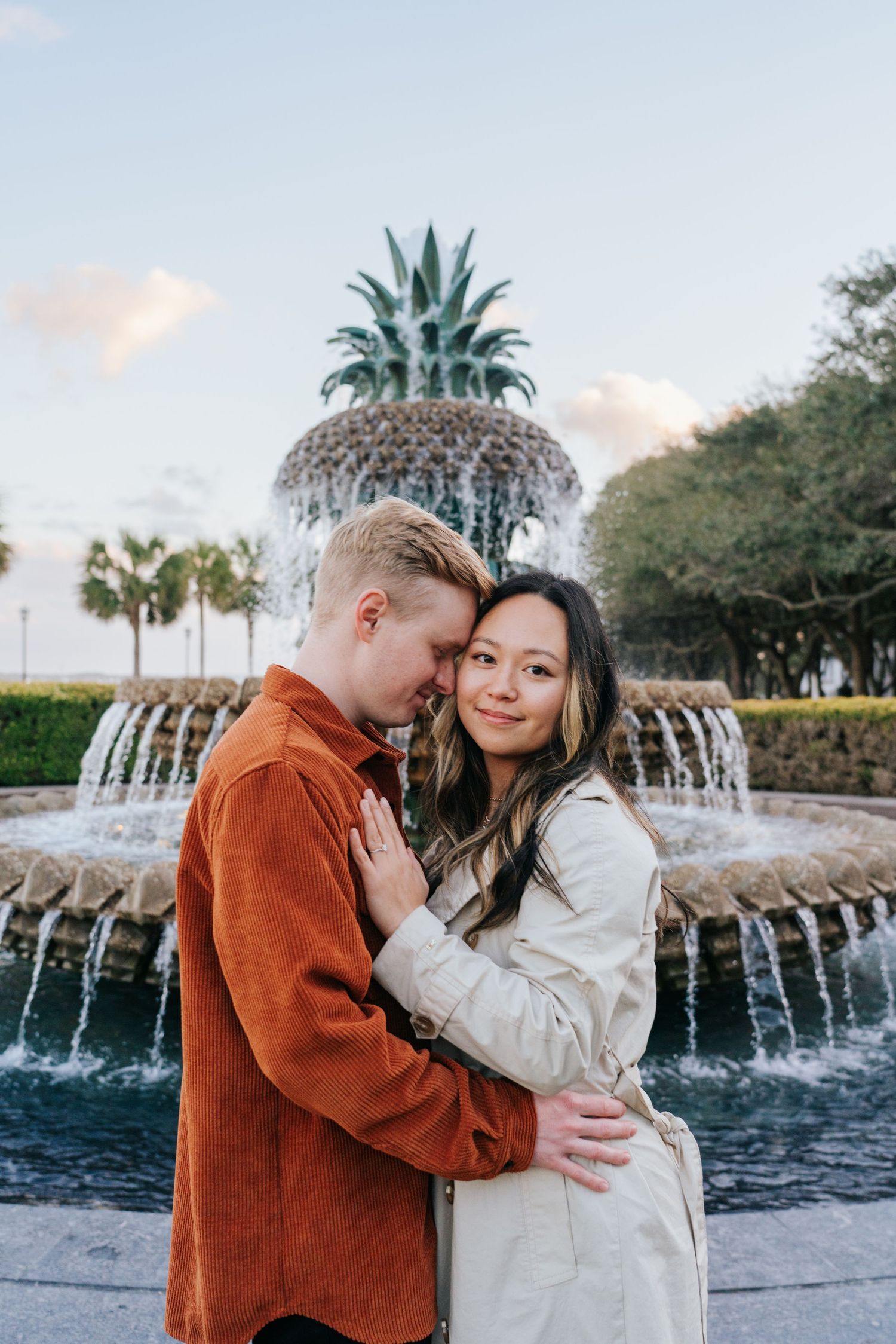 Engagement photos by the iconic Pineapple Fountain in Charleston with couple in casual attire.