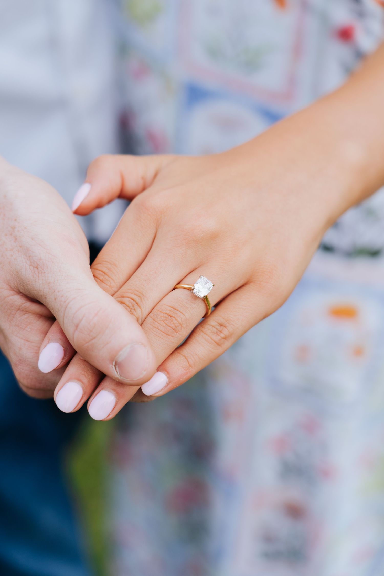 Close-up shots of hands displaying an engagement ring against a patterned background.