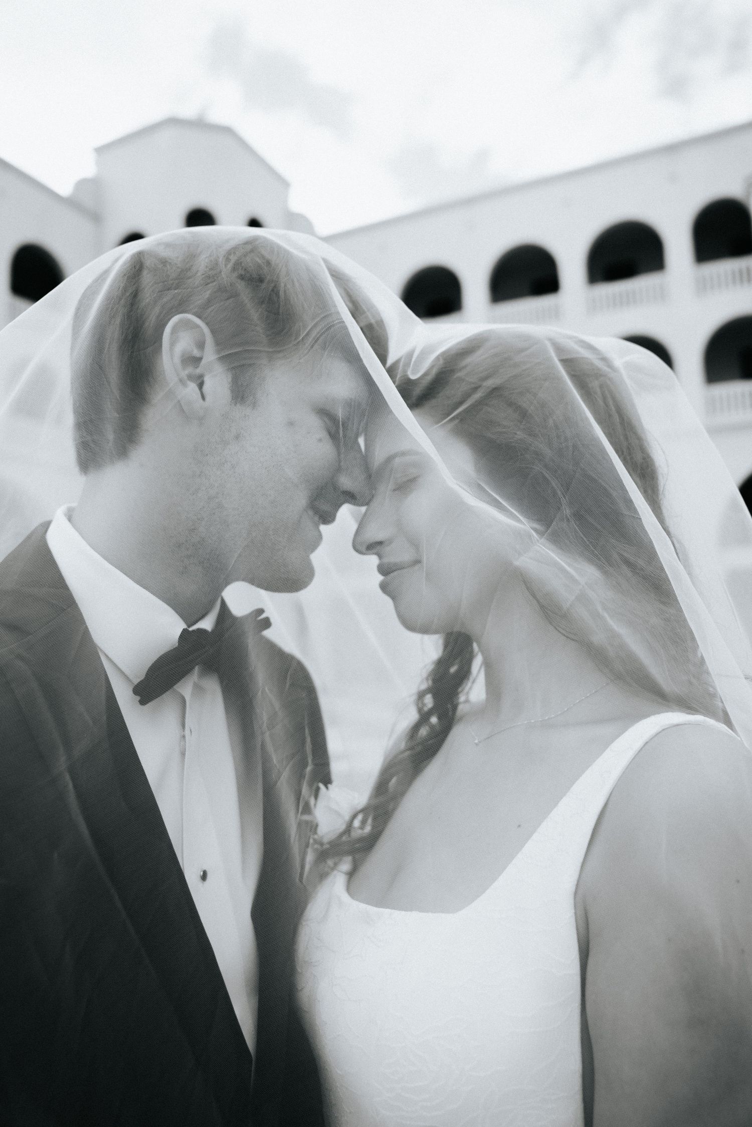 Artistic black and white series of intimate wedding moments against white architecture.