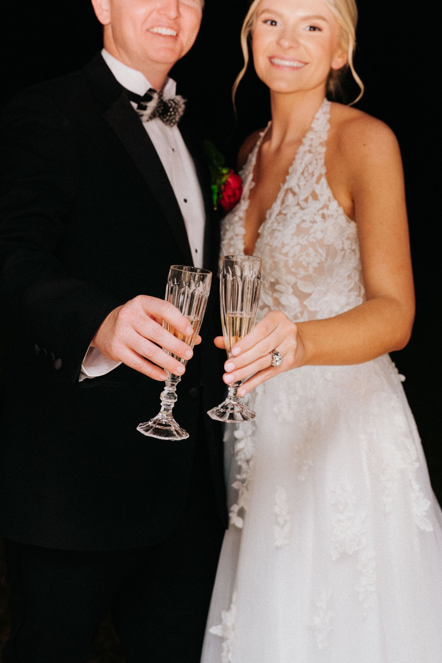 Newlywed couple toasts with champagne glasses during wedding reception celebration.