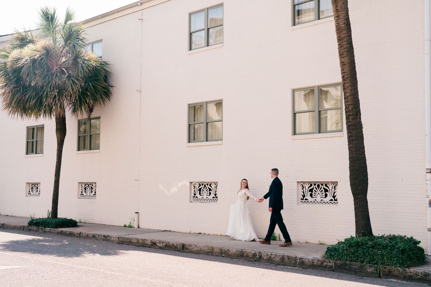 A minimalist exterior view of a white building with palm trees.