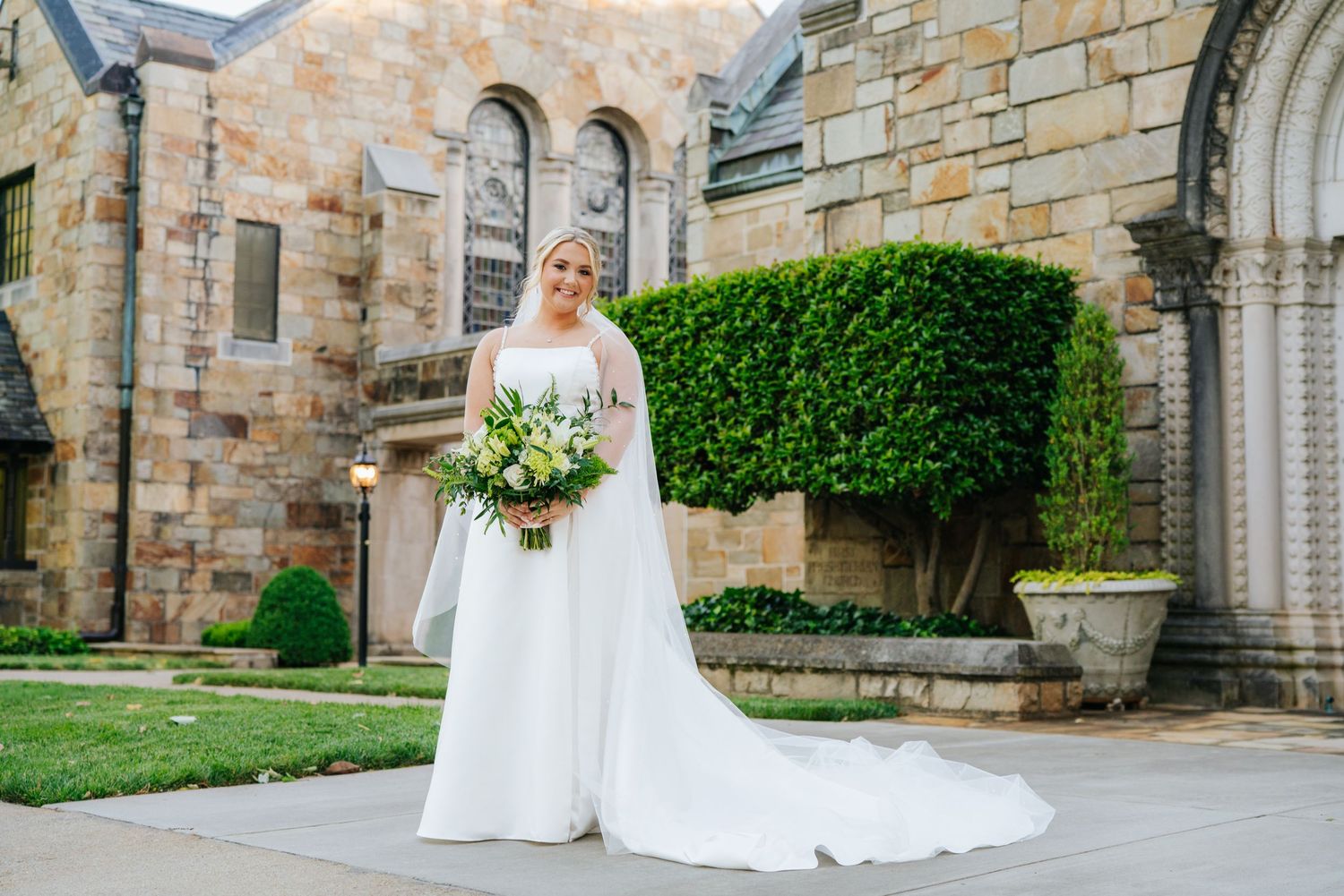 Classic bridal portrait outside stone church with architectural details.
