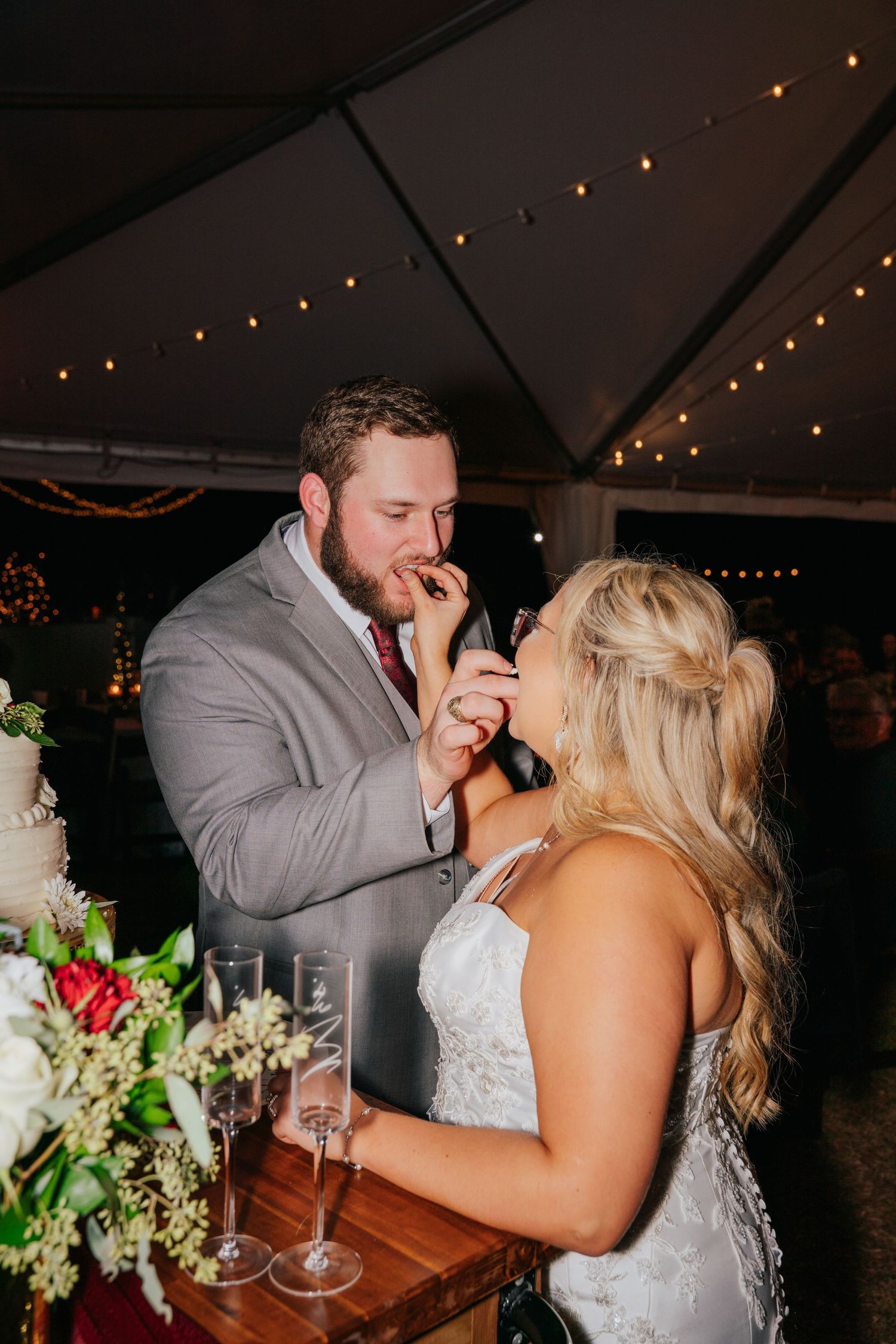 A romantic moment shared between a couple during their wedding reception under twinkling string lights.