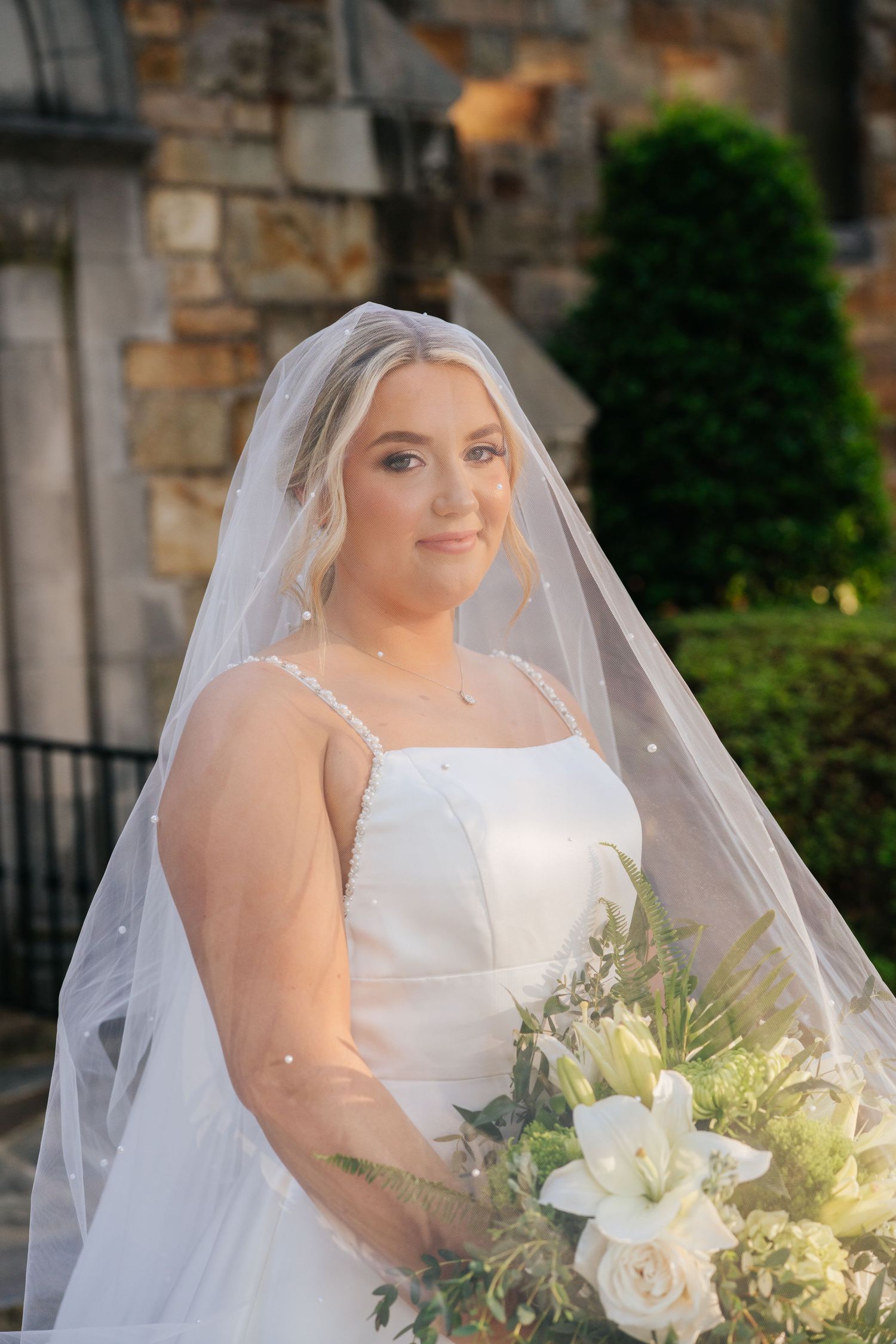 Beautiful white wedding bouquet with roses and greenery against classic bridal gown.