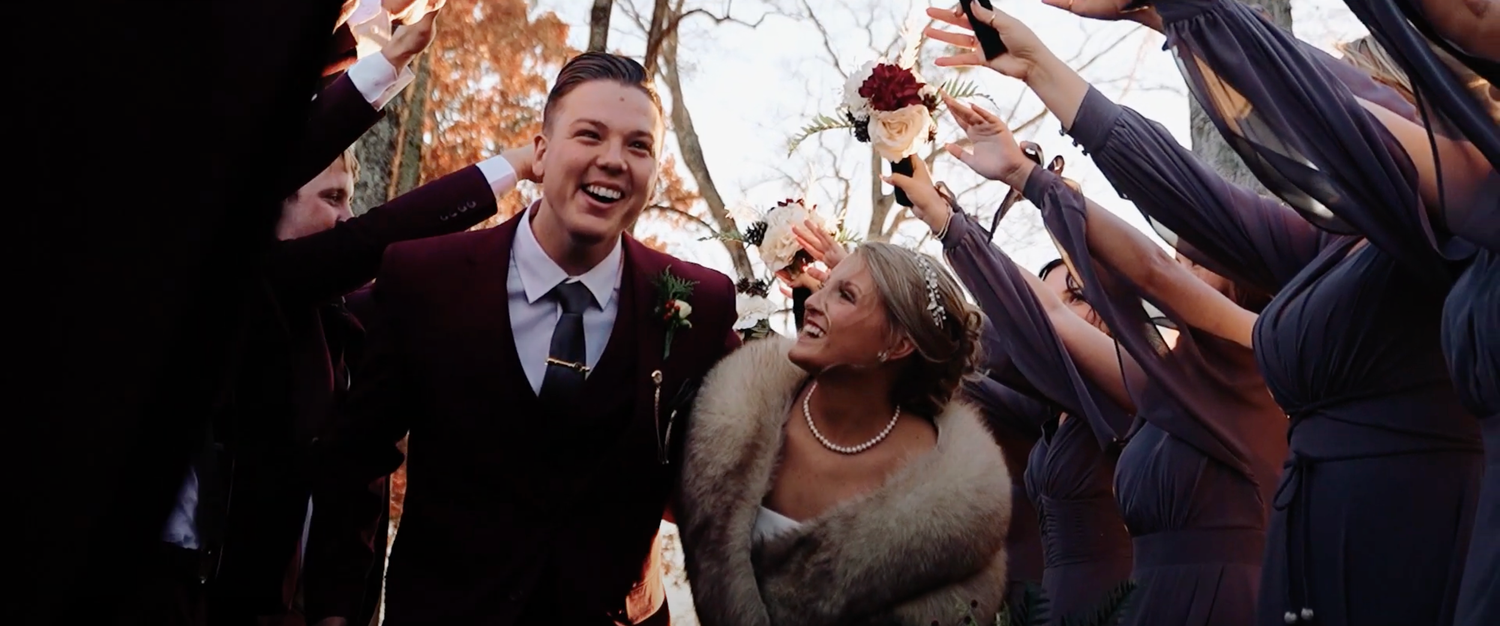 Wedding celebration with joyful couple surrounded by guests raising their hands in celebration.