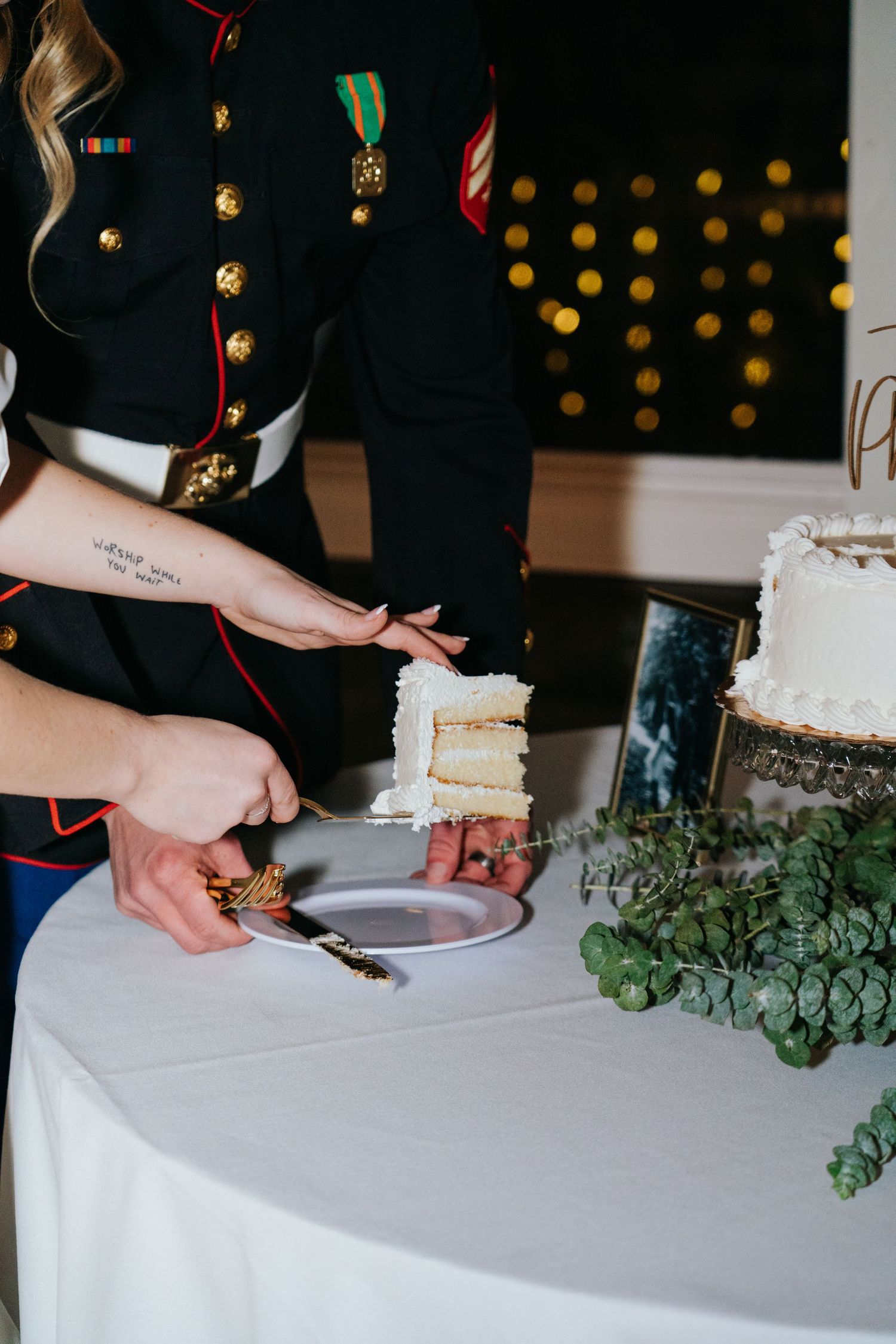 Close-up shots of hands cutting a white wedding cake decorated with greenery.