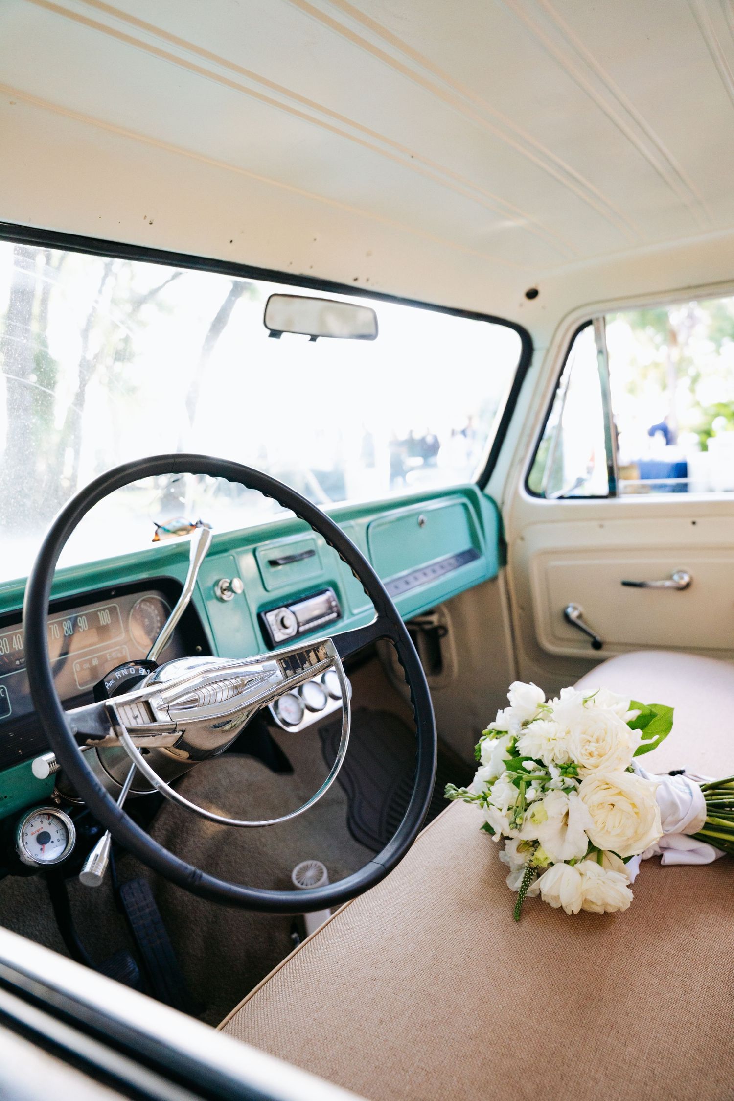 Interior view of a vintage truck dashboard with white flowers placed on the brown upholstery.