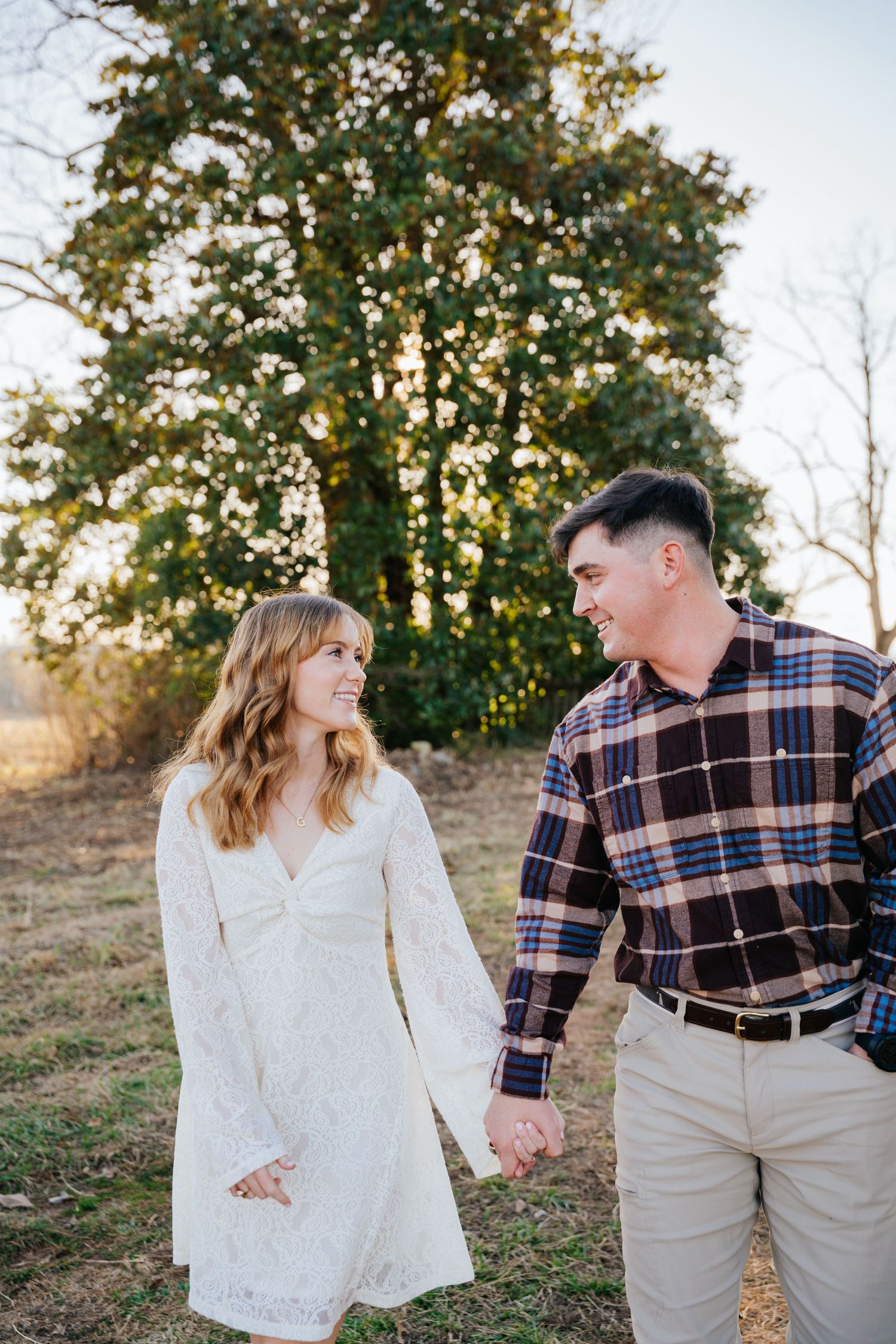 A couple shares a joyful moment together outdoors during a sunset photoshoot in autumn.