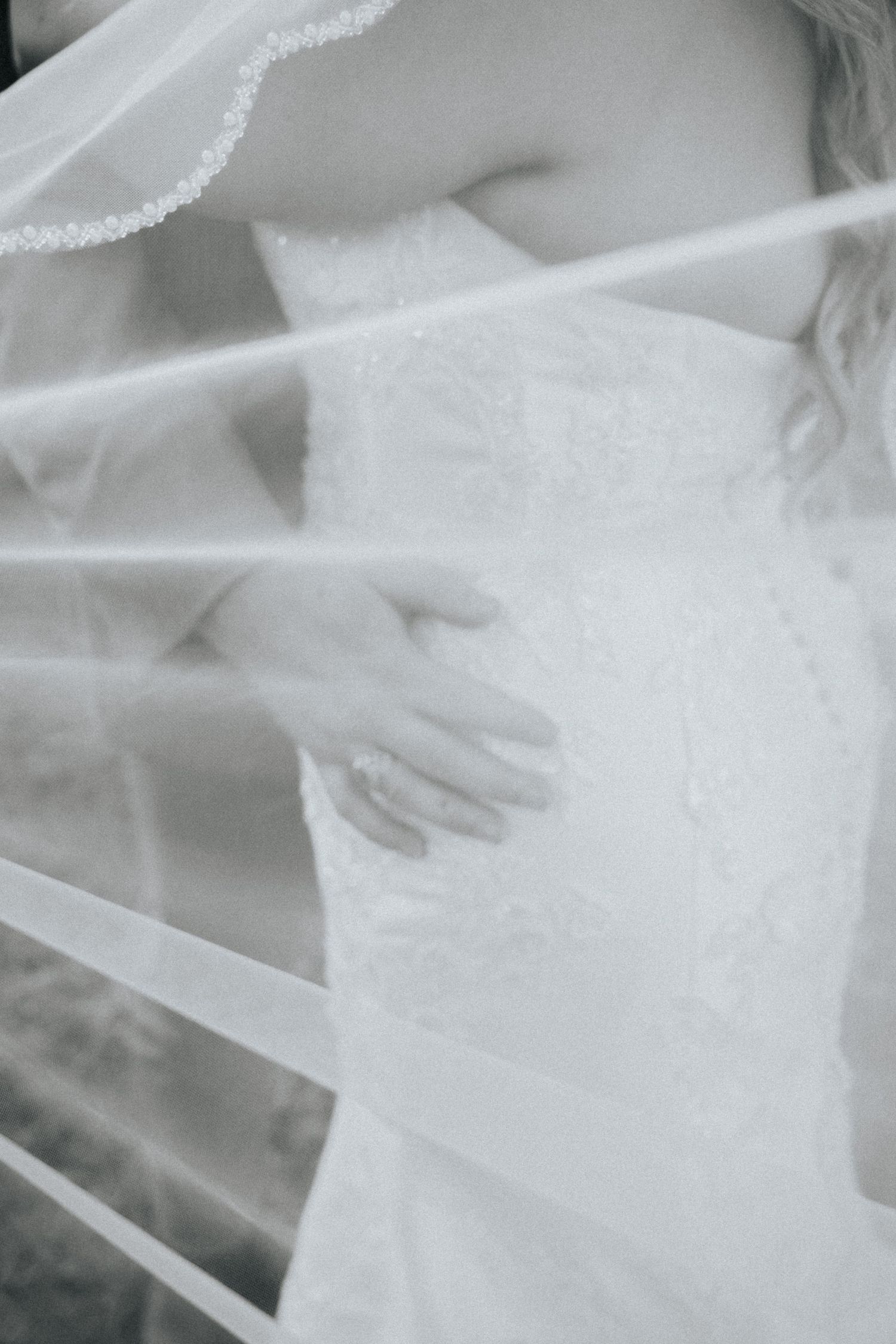 Ethereal black and white close-up of delicate white fabric or veil with soft folds creating an abstract pattern.