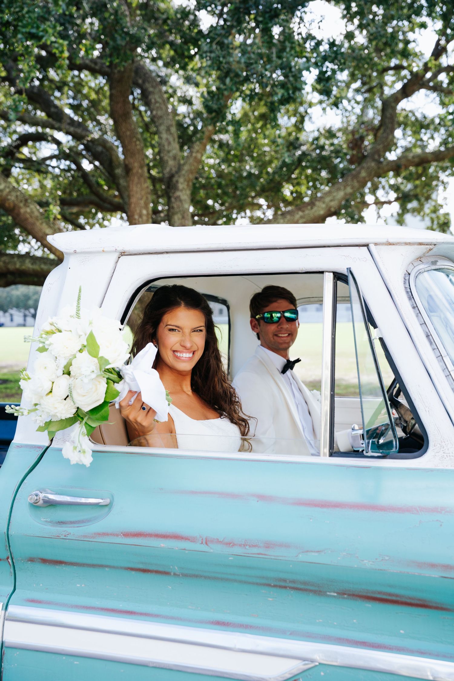 A classic mint green vintage truck decorated with white flowers serves as wedding transportation.