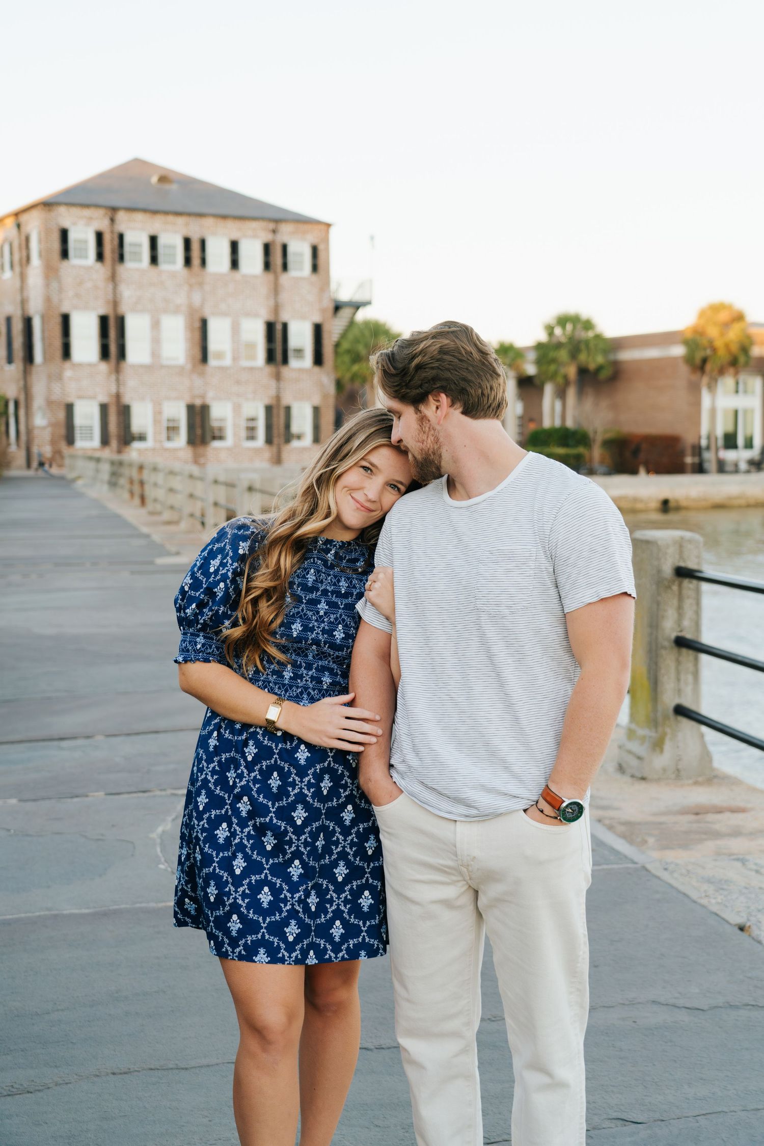 A couple in coordinated outfits sharing tender moments by the waterfront.