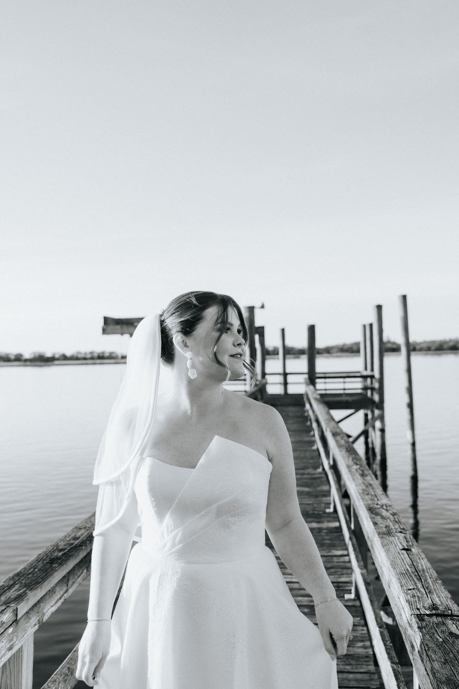 Black and white bridal portraits captured on a wooden dock by the water.
