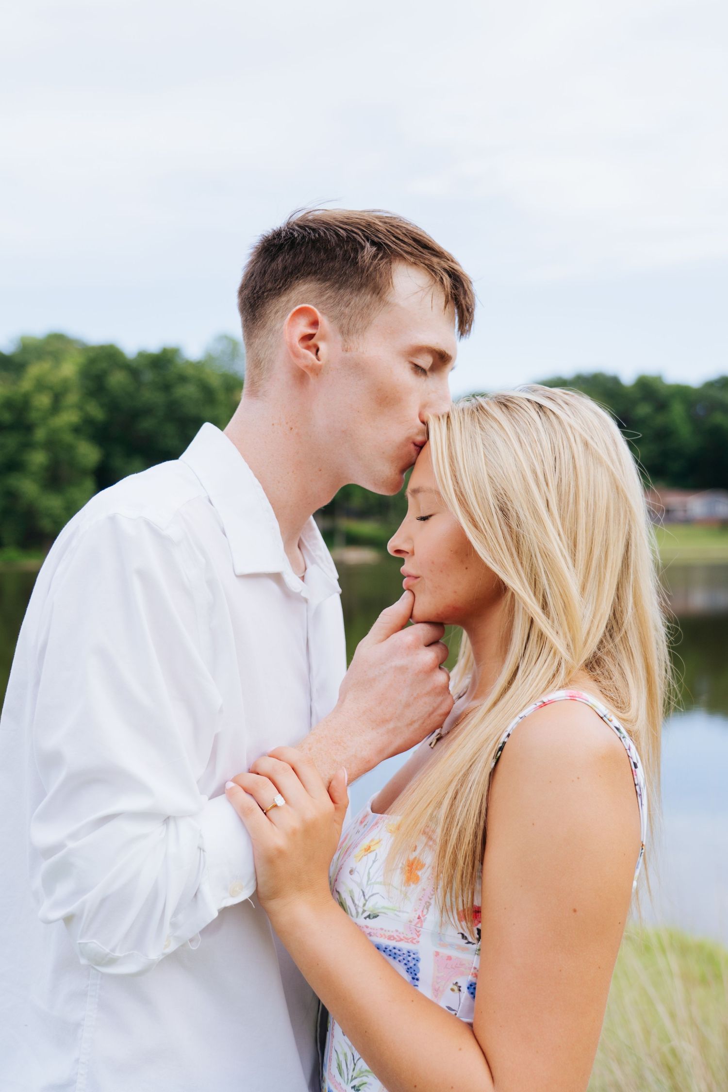 Romantic couple sharing an intimate moment by a serene lake on a summer day.