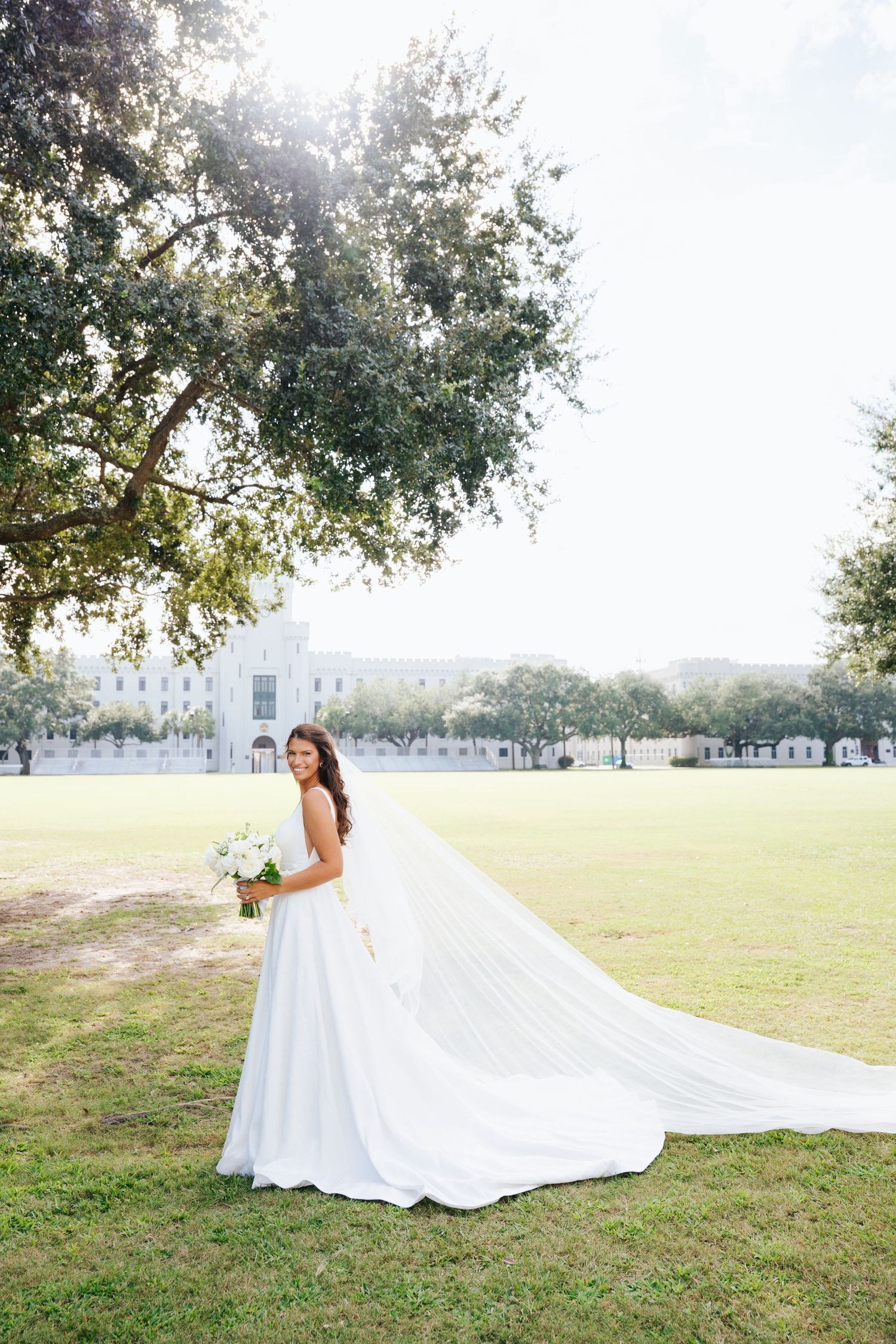 Sun-drenched bridal photos on the Citadel lawn with white dress train flowing behind.