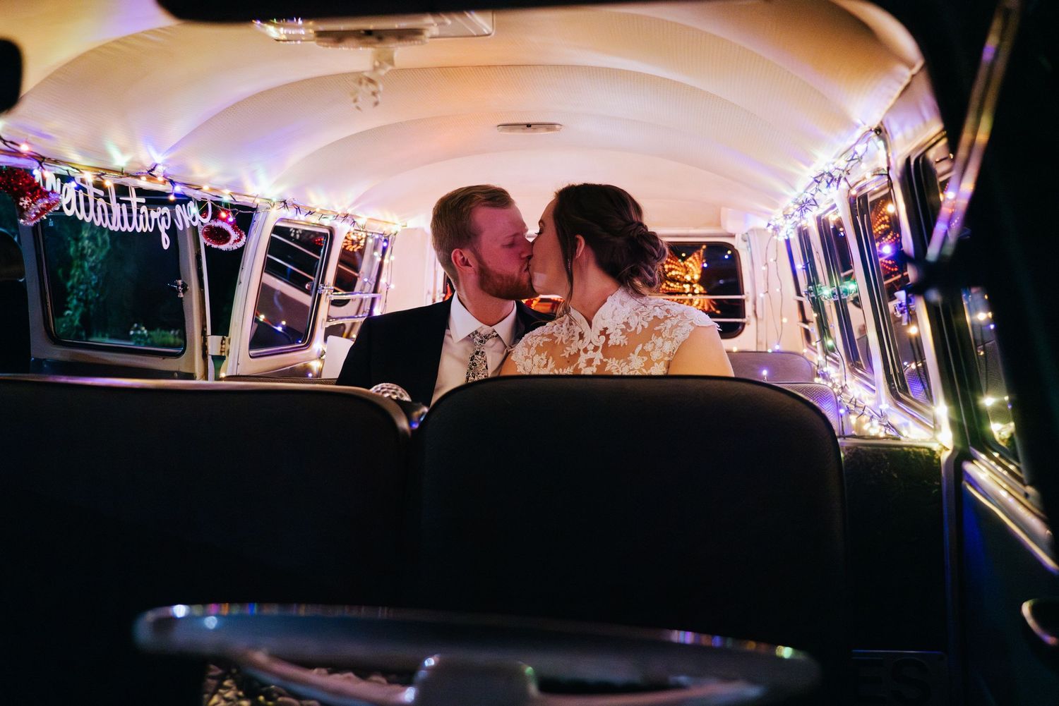 Party bus interior lit with purple lights during wedding celebration.