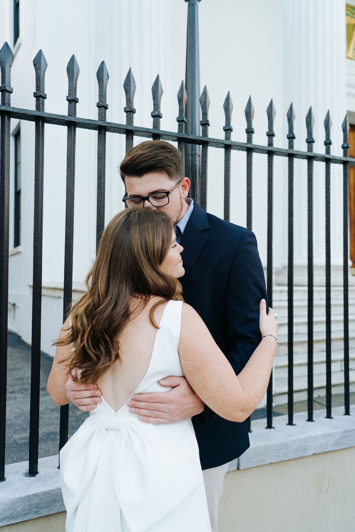 A romantic moment captured between a couple by a decorative iron fence.