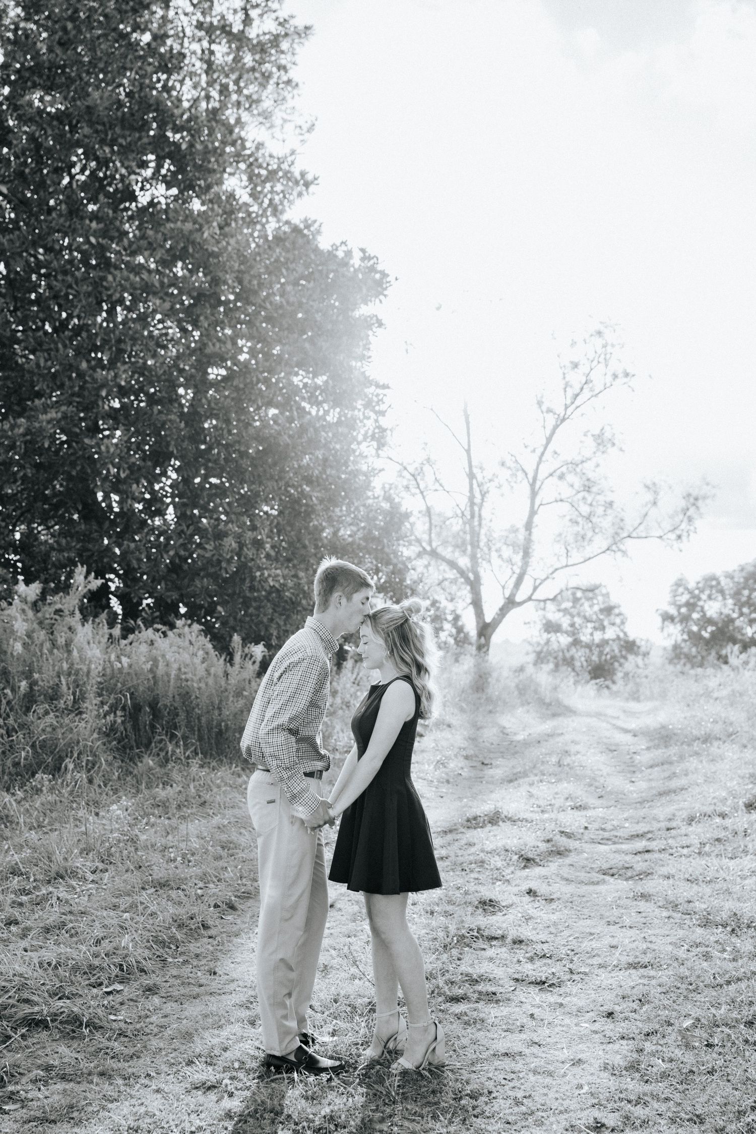 Two figures stand together on a misty hillside in black and white, creating a dreamy romantic atmosphere.