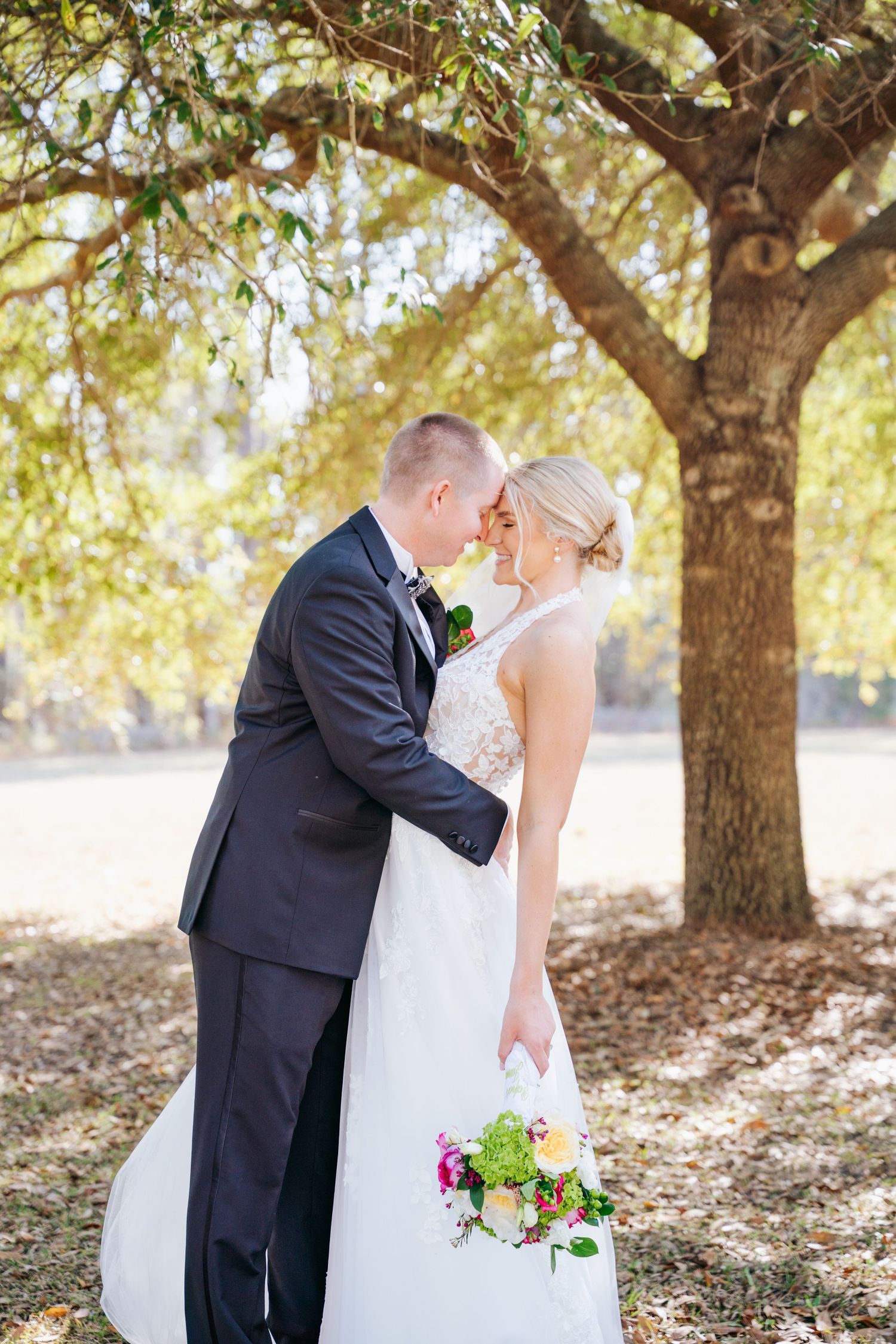 A romantic wedding photo series captured under blooming trees showing tender moments between newlyweds.
