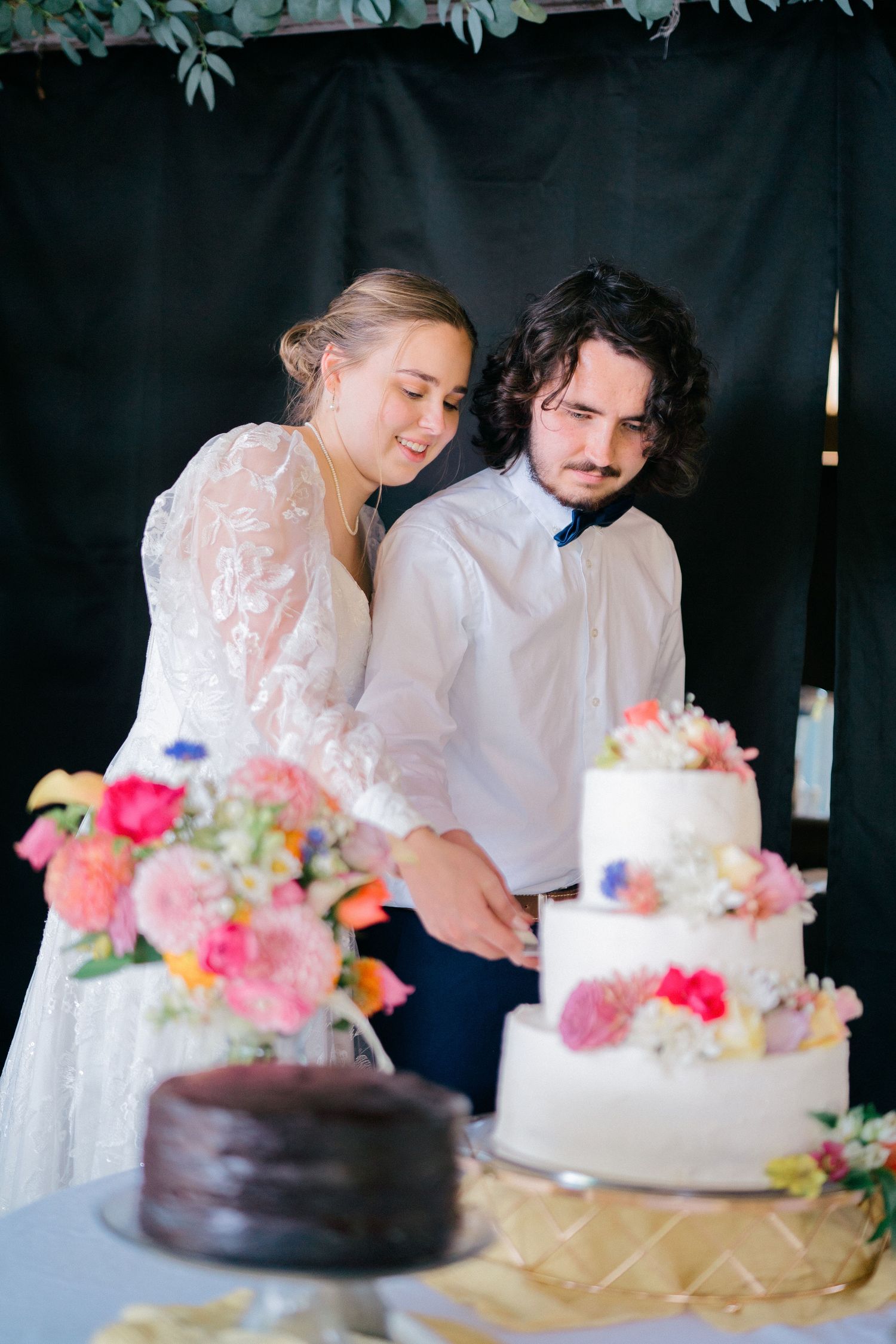 Wedding couple cutting their floral-decorated wedding cake together.