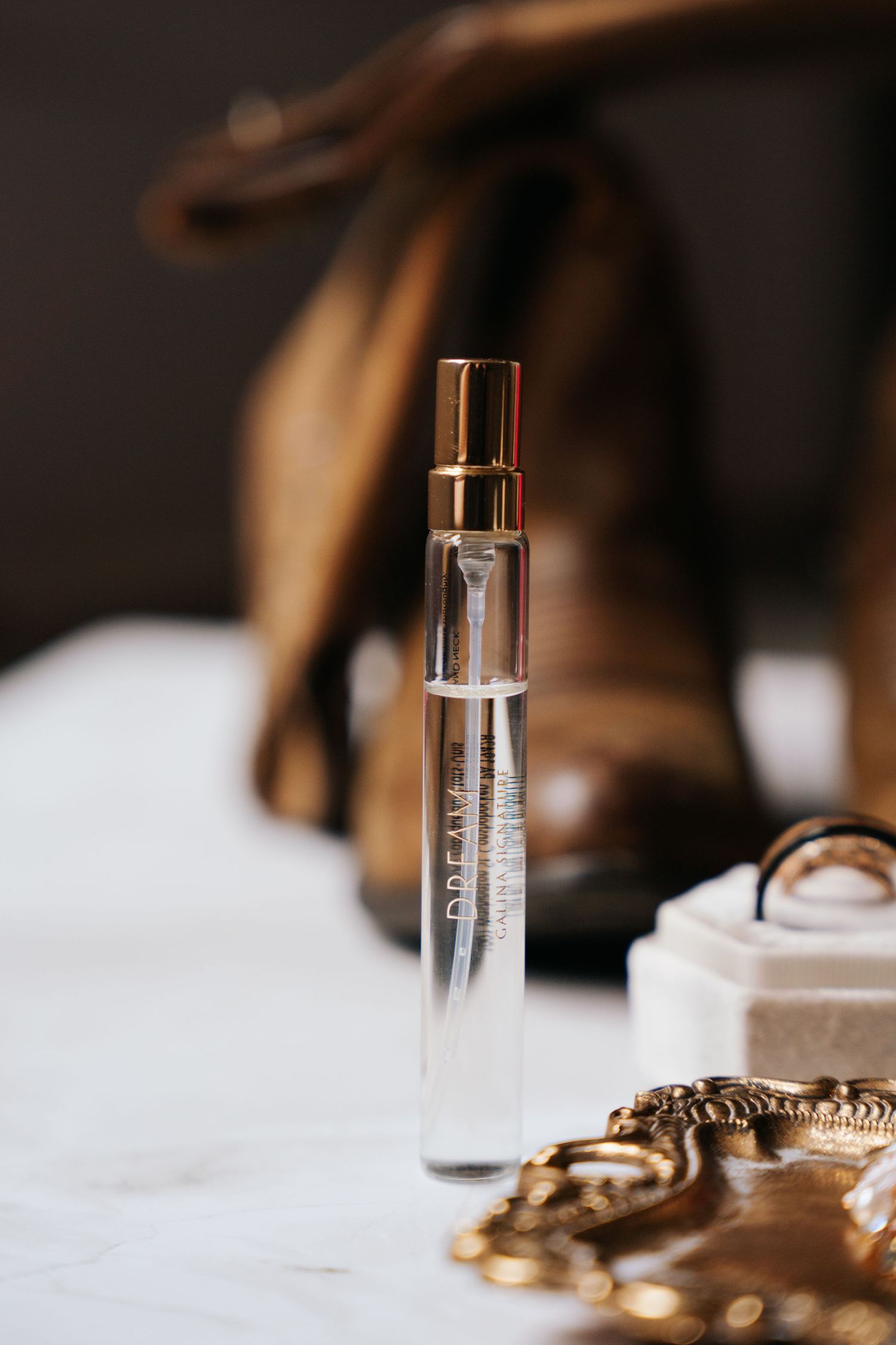 Perfume bottles and gold jewelry arranged on white surface with soft blurred background.