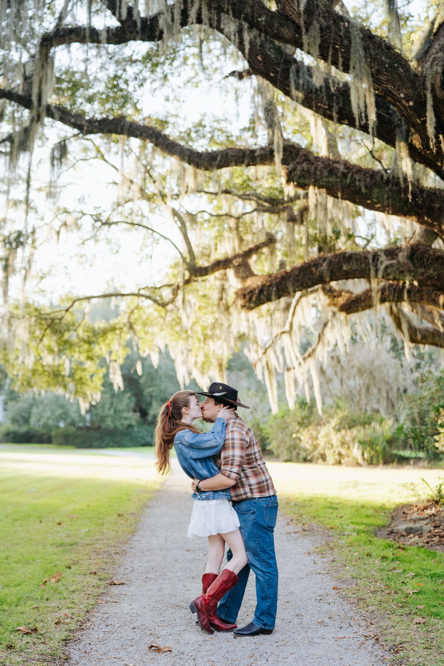Romantic embrace on a path beneath Spanish moss draped oak trees.