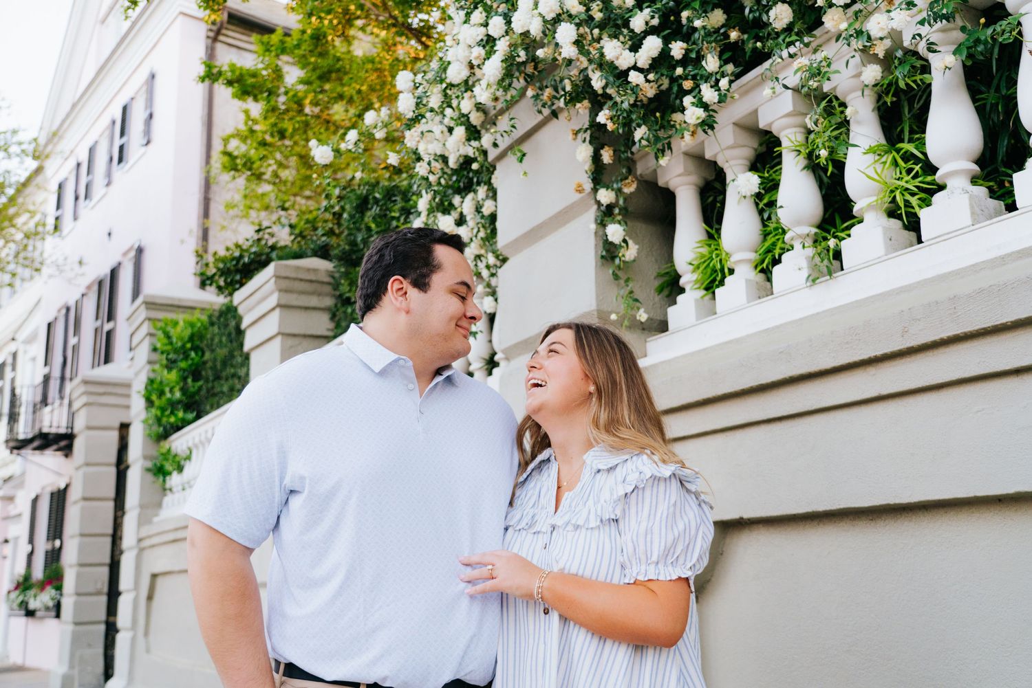 Couple shares romantic moments on a white columned porch with flowering vines.
