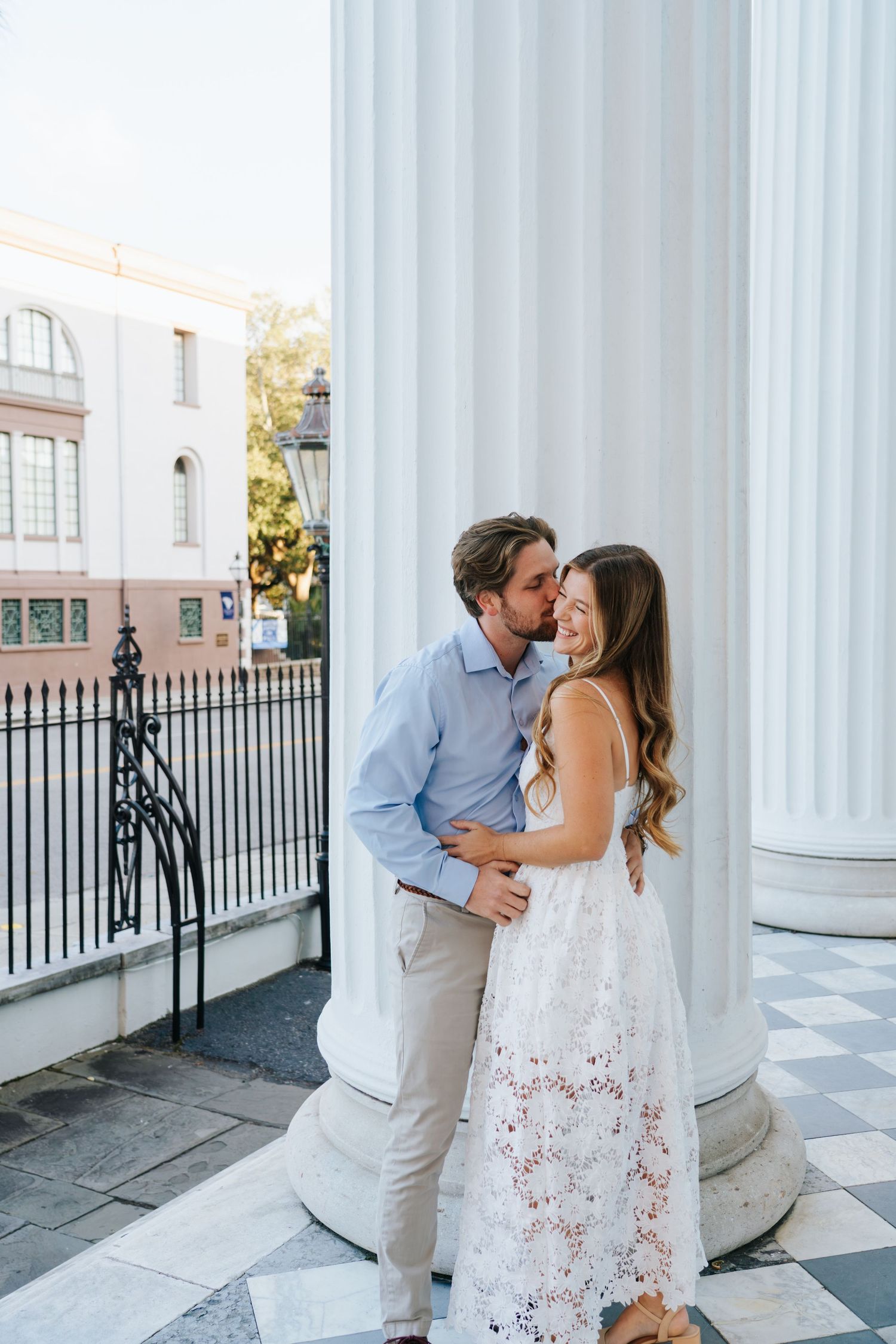 A romantic moment captured between a couple among white columns of a historic building.