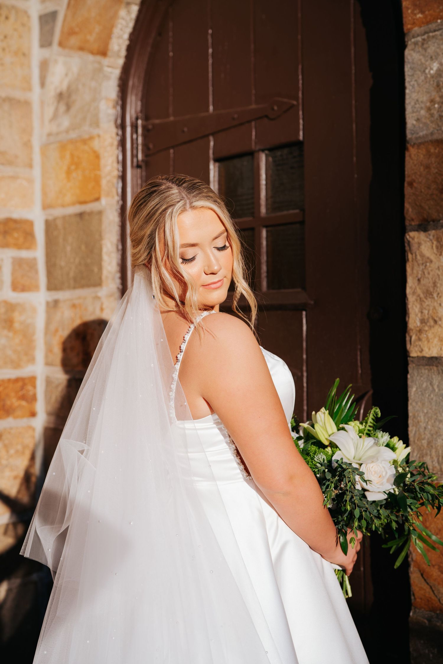 Intimate bridal portrait against rustic stone wall and wooden door.