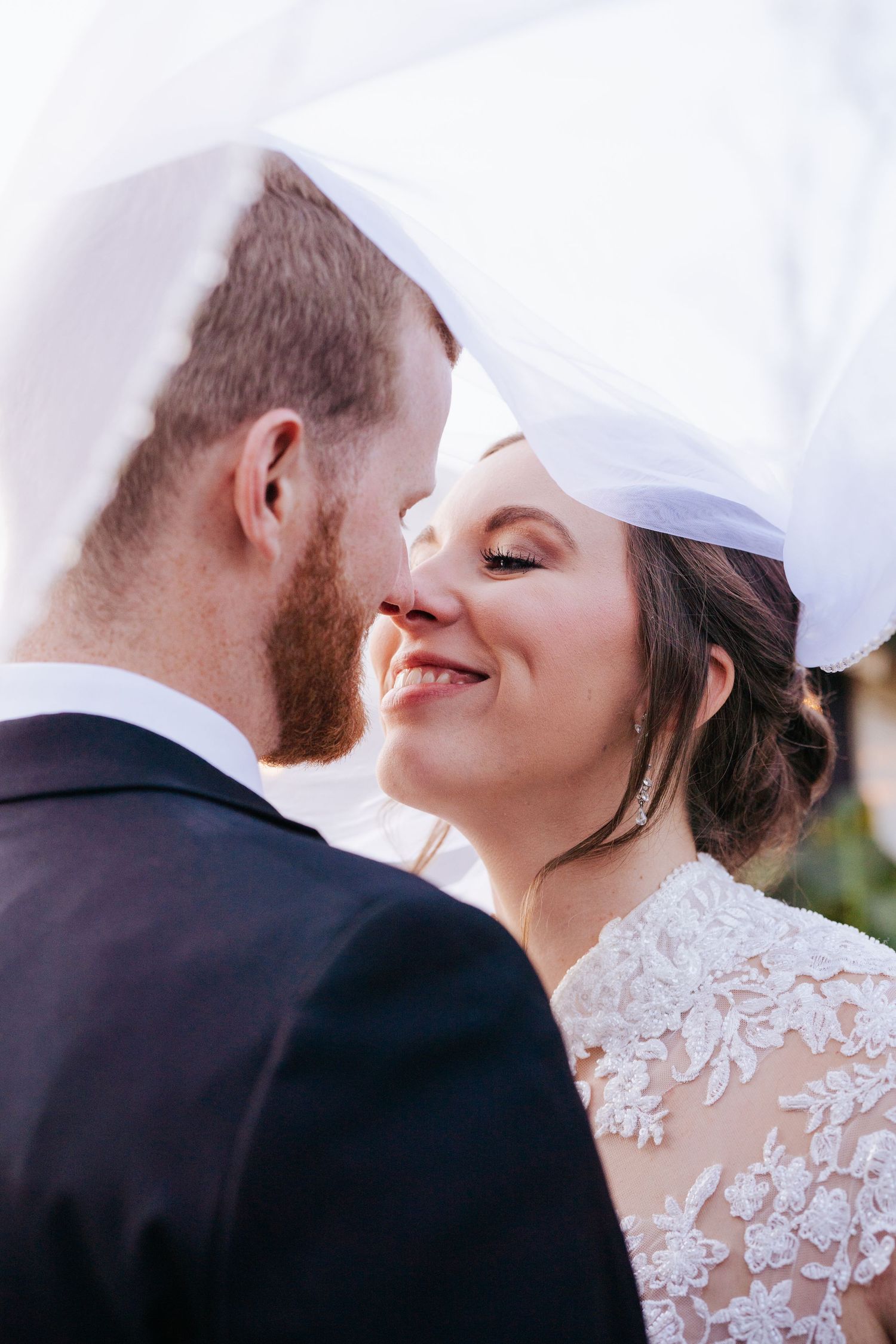 Intimate wedding moment captured under a white veil during the ceremony.
