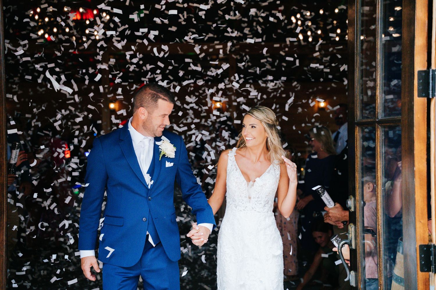 White confetti falls around a couple celebrating during their wedding ceremony.