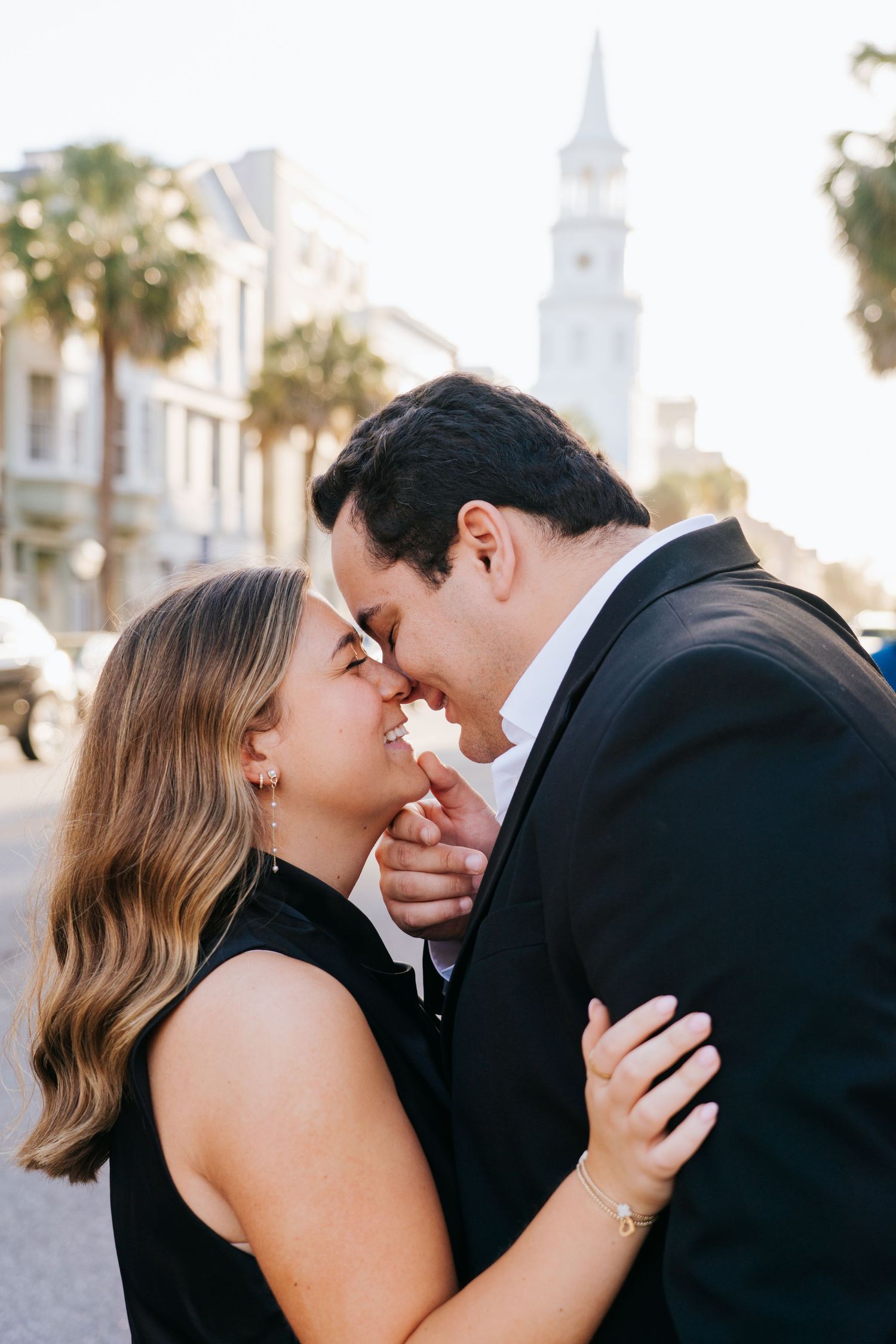 Romantic couple shares intimate moments against a backdrop of white church steeples and palm trees.