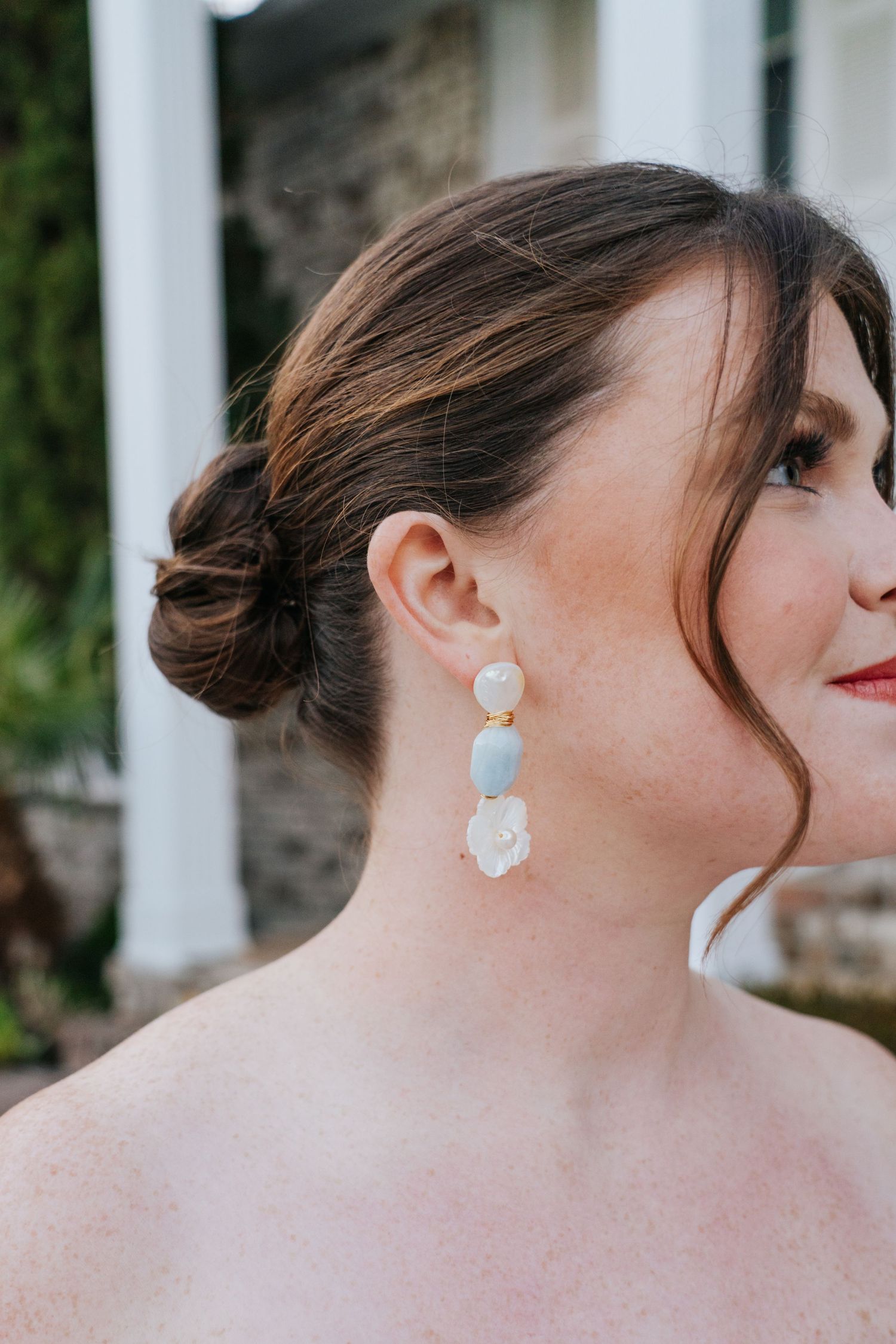Pearl earrings and elegant bridal makeup are showcased in a close-up portrait.