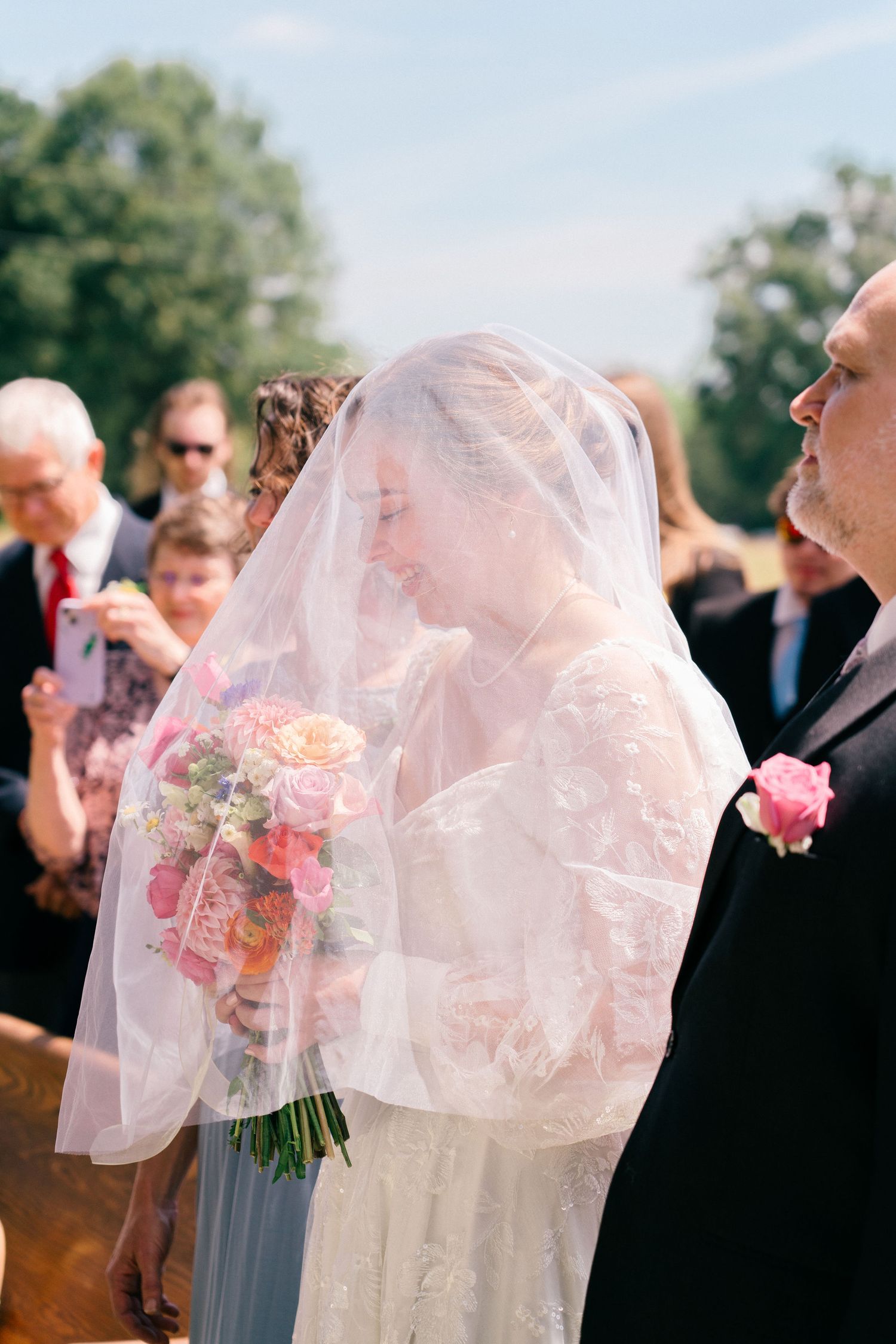 Wedding ceremony guests watch as couple shares intimate moments under a flowing veil.