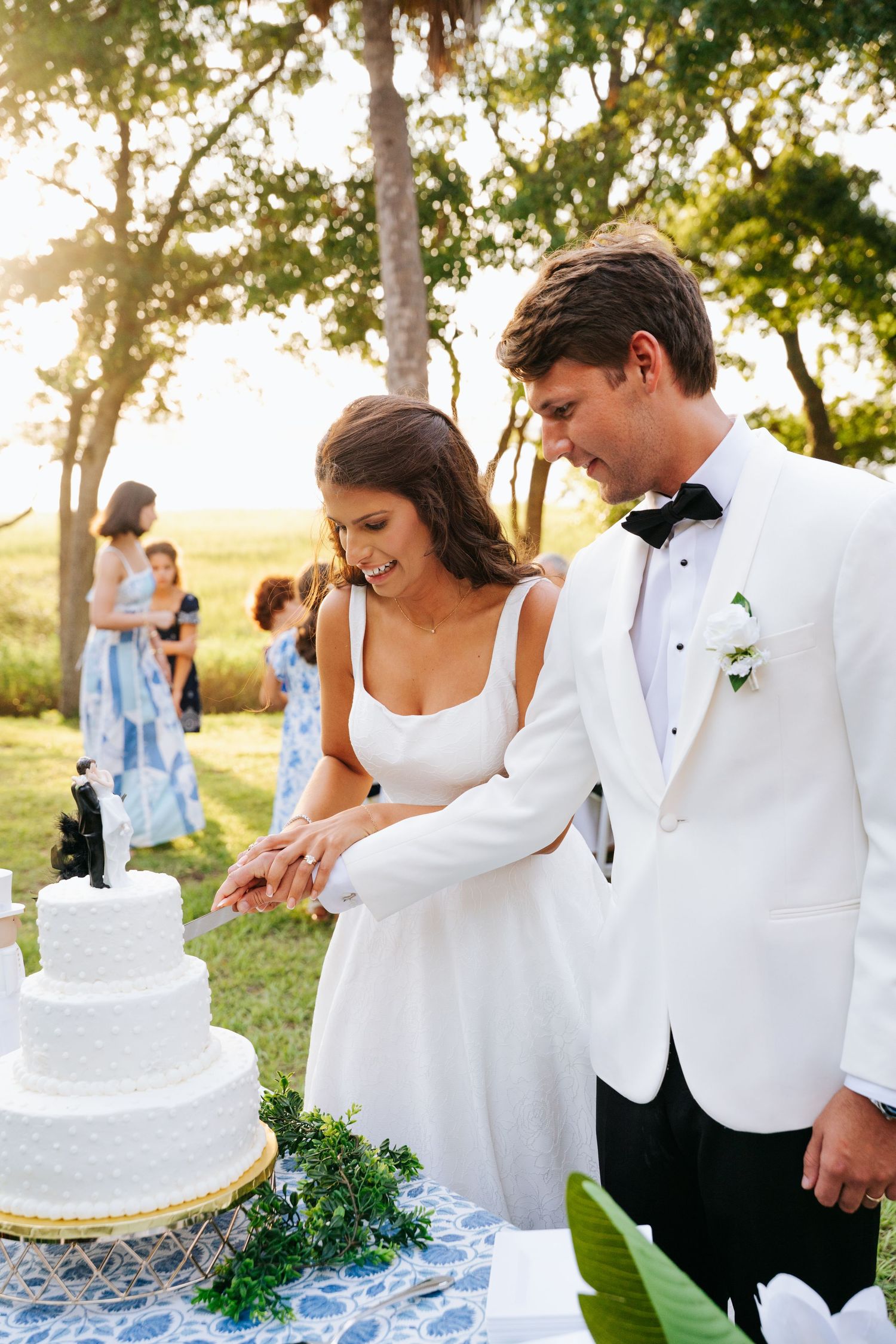 Newlyweds cutting their white wedding cake together in a personal backyard wedding setting.