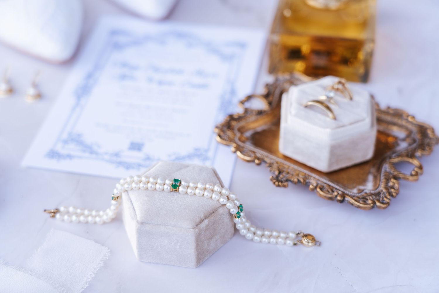 Wedding accessories including pearl jewelry and delicate boxes arranged on white fabric.