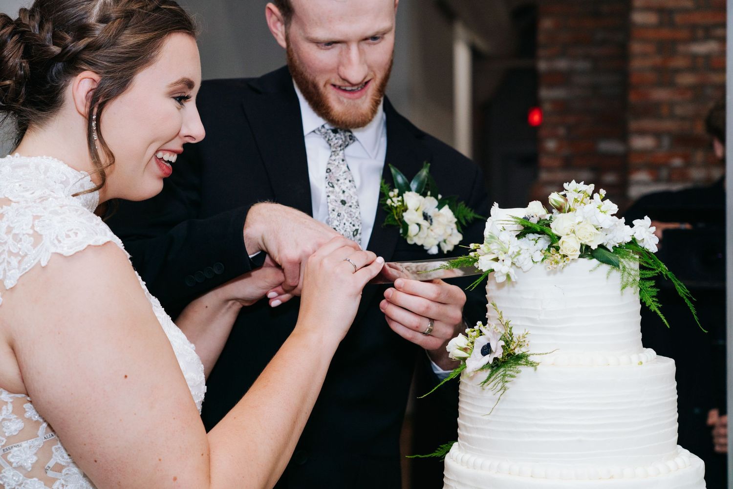 Couple shares intimate moment while cutting their white wedding cake.
