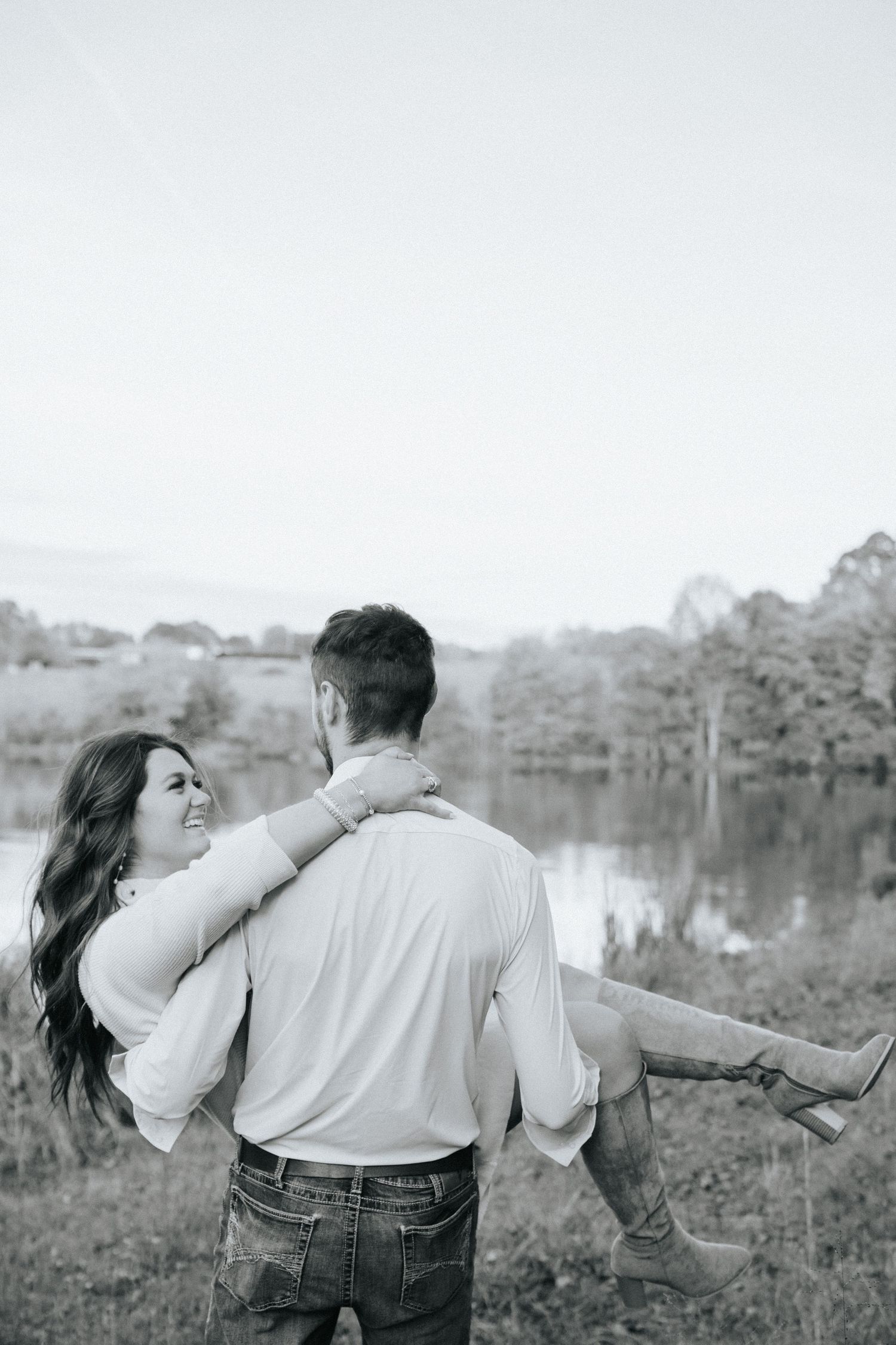 A romantic black and white sequence shows a couple embracing and dancing playfully by a serene lake.
