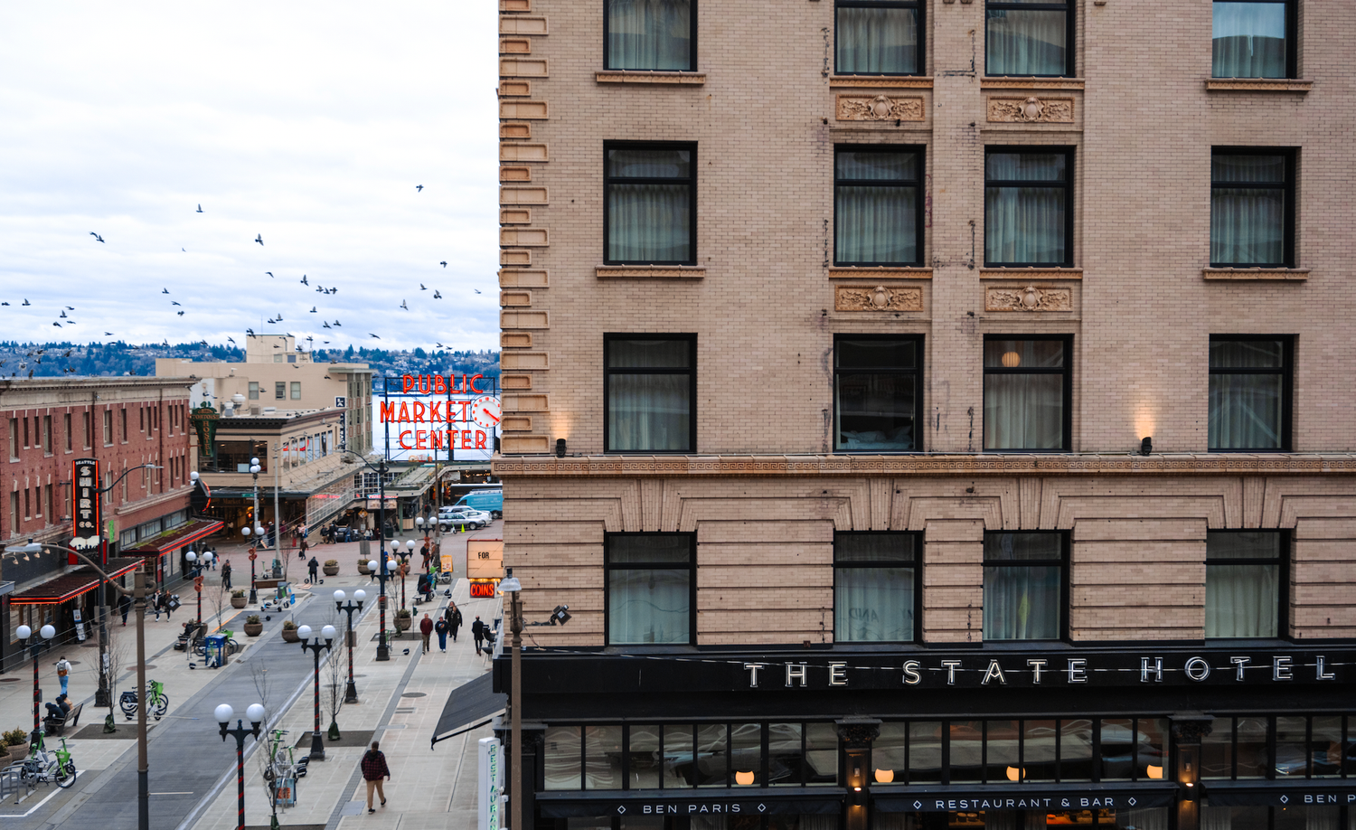 An urban view of The State Hotel building facade with city street and flying birds in Seattle.