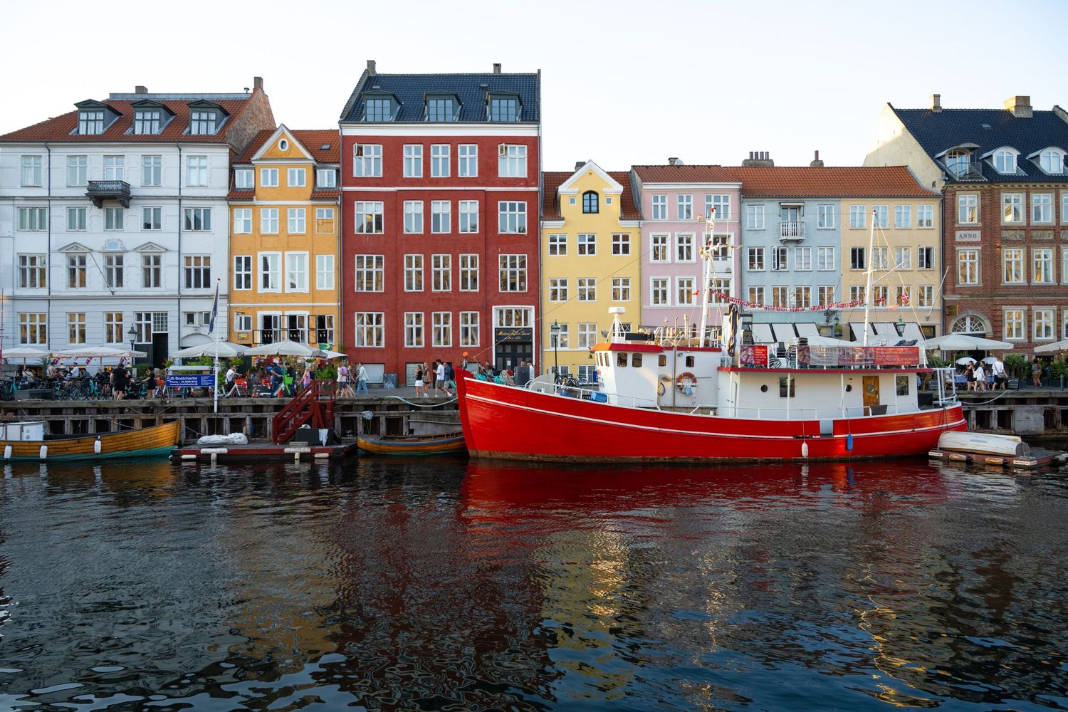 Colorful historic waterfront buildings reflected in the harbor water at Nyhavn canal in Copenhagen, Denmark.