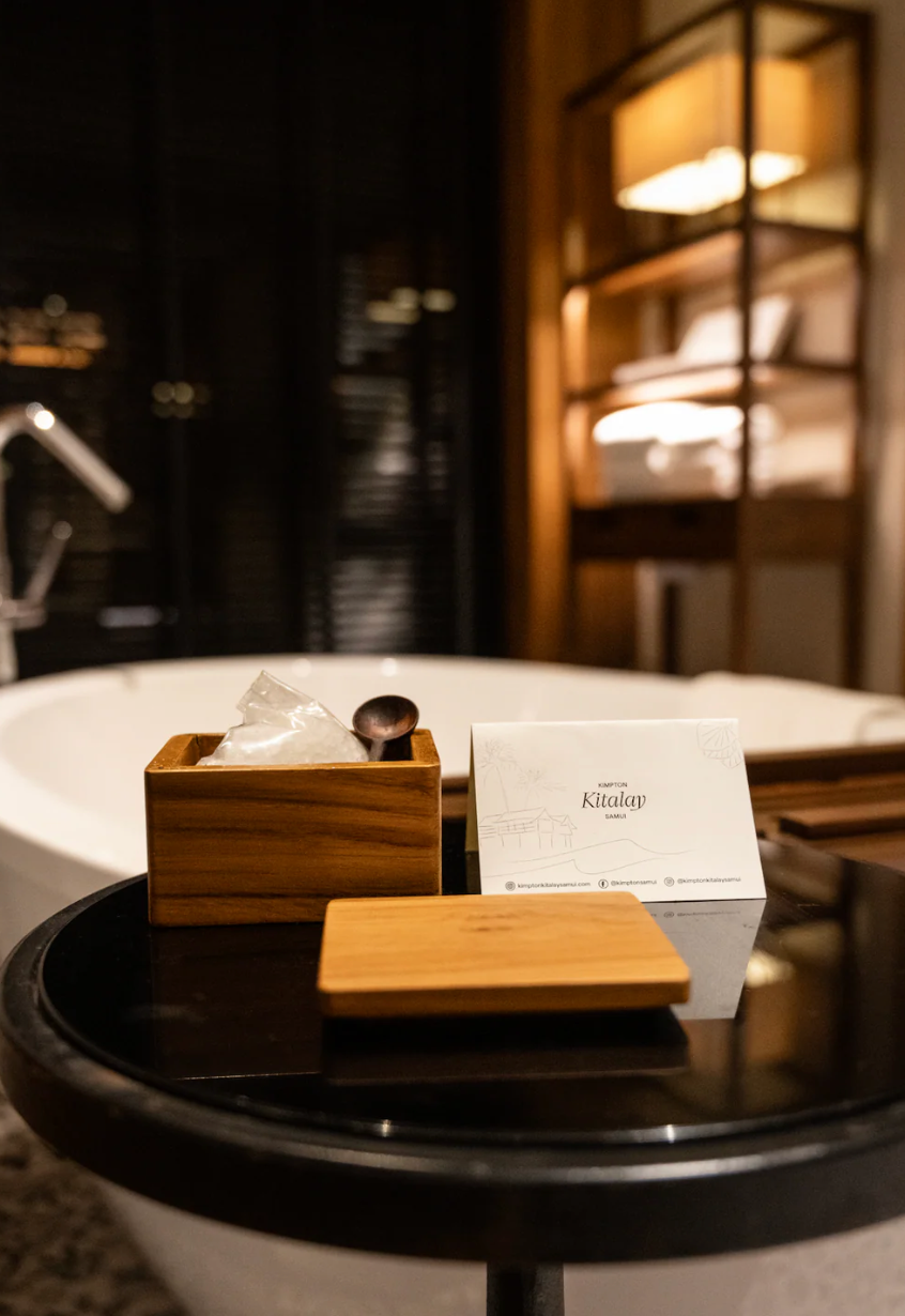 Close-up view of ambient bathroom and bath salts with wooden accessories in warm lighting.