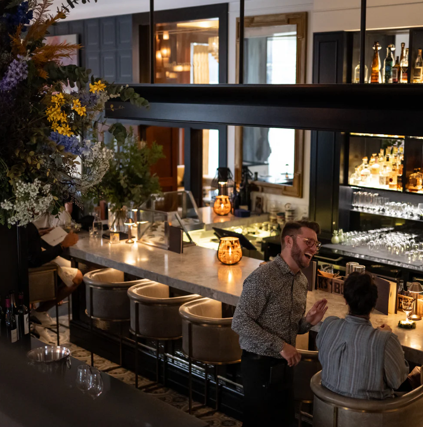 Dimly lit luxury hotel bar with elegant seating and ambient lighting.