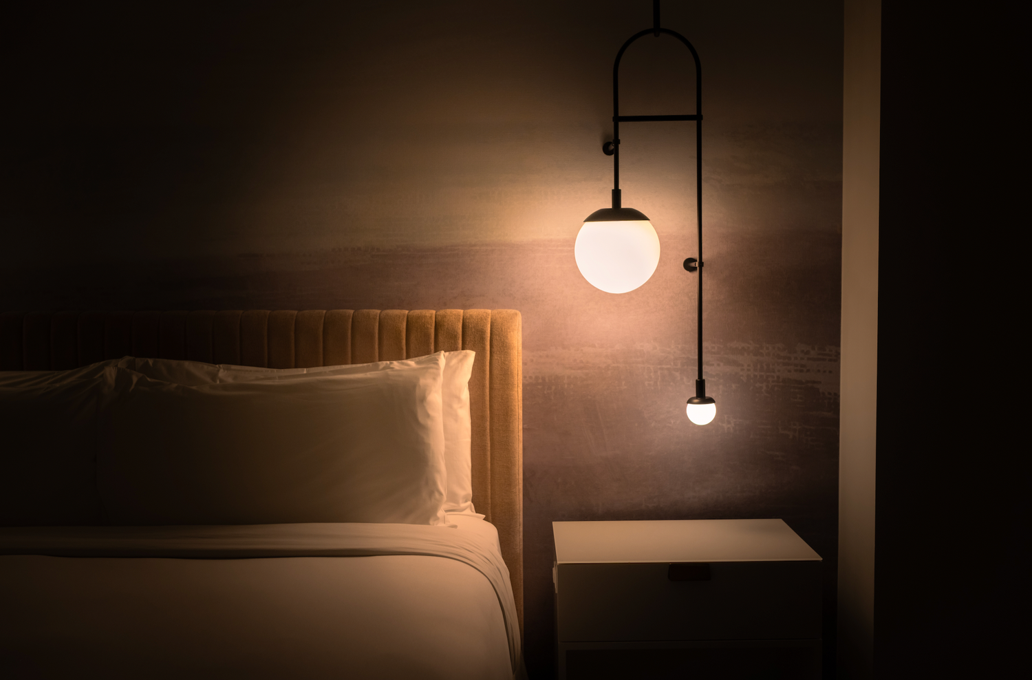Modern minimalist bedroom with warm glowing pendant lights creating cozy ambiance.